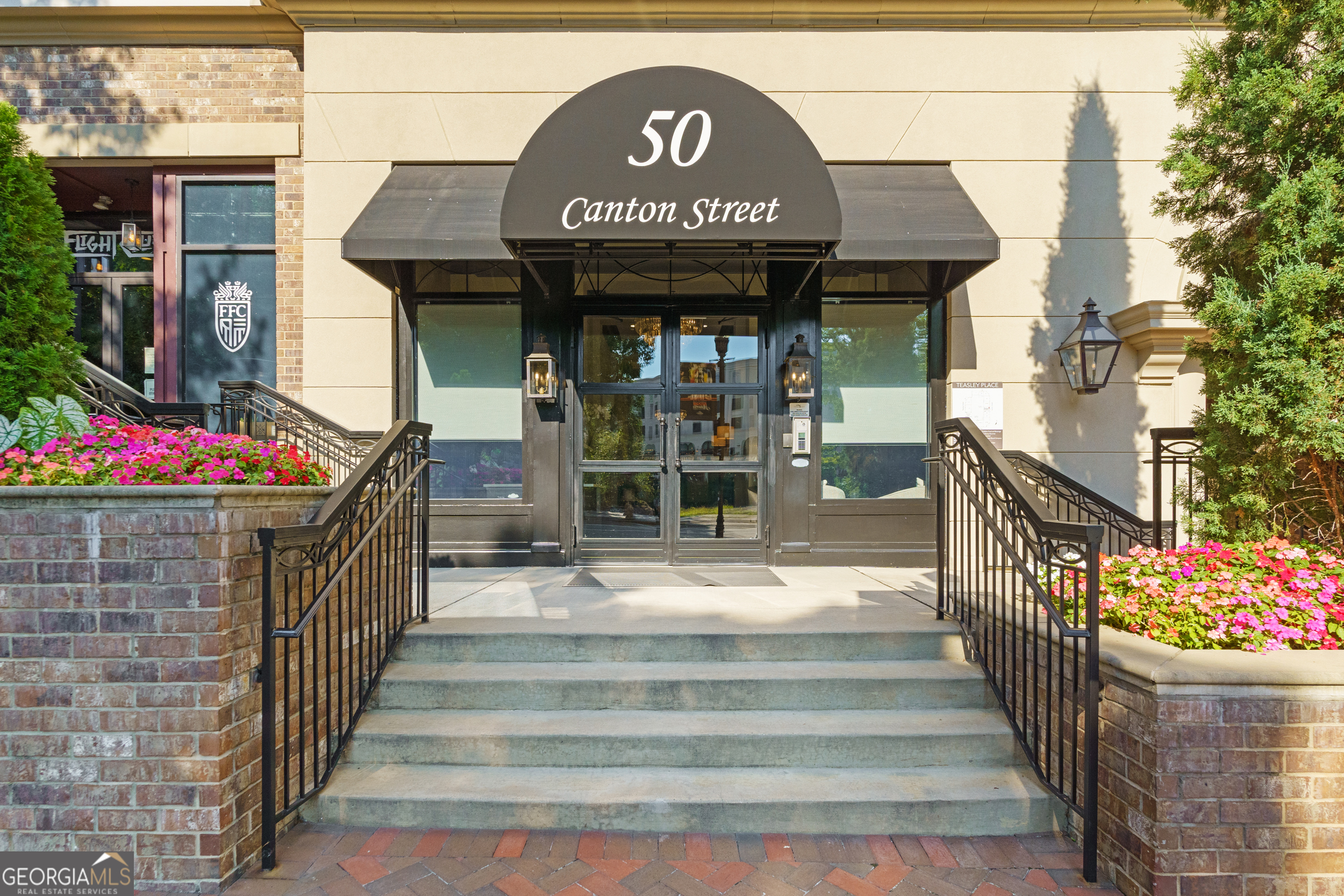 Experience luxury living in the heart of downtown Alpharetta with this beautifully appointed condo at Teasley Place. Perfectly situated within the building for added peace and quiet, this home pairs elevated finishes with the ease of one-level living-just steps from dining, shopping, and the farmers market. Inside, the open floor plan is designed for both everyday comfort and effortless entertaining, complete with Smart home features like a Control4 Home Automation System and Nest Thermostat. The chef's kitchen boasts quartz countertops, a Sub-Zero refrigerator, Wolf gas range, trash compactor and premium appliances. Natural light pours in, highlighting wide-plank hardwood floors, custom cabinetry, plantation shutters, and built-in storage throughout. A separate office space offers a quiet place to work or unwind. From the main living area, step onto your private covered patio, facing west in the afternoons for picture-perfect sunsets. Outfitted with its own fireplace and built-in grill, it's an ideal setting for a game day gathering or a quiet evening outdoors. The oversized primary suite is a true retreat with a spa-like bath and a California Closet system for added organization, while the additional bedrooms provide flexibility and privacy, whether used as guest suites, an office, or versatile flex space. Practicality meets convenience with two secured parking spaces equipped with an EV charger, along with a large, climate-controlled storage unit. Beyond the walls of your home, Teasley Place offers unmatched community amenities-from Teasley Park with its outdoor kitchen, pavilion, and Big Green Egg to the Bocci and Corn Hole courts, fully equipped gym, dog park, and on-site building management-all designed to extend your living space and bring neighbors together. With its upscale finishes, low-maintenance lifestyle, and walkable access to everything downtown Alpharetta has to offer, this home balances refinement, connection, and comfort in one of the city's most coveted addresses.