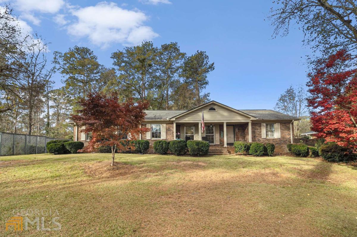 This attractive 4-sided brick ranch home with hardwoods throughout is setback on almost a 1/2-acre lot with a large front yard and level fenced backyard with a serene backdrop. Magnificent Japanese Maples and a charming front columned porch give this more curb appeal than you will be able to handle. The tastefully updated eat-in kitchen is the heart of this home featuring stylish granite countertops, white cabinetry, a kitchen island and a separate prep station - or wet bar - with additional sink. The Dishwasher and Gas Range have been recently replaced. The kitchen has views to the large beautiful den with built-ins, fireplace, wood mantel beamed ceilings and a uniquely charming brick floor. Oversized room in the front of the house can be used for formal dining and formal living or even a wonderful bright open office space. As if that wasn't enough, this home features a glorious sun room overlooking your expansive multi-level deck and peaceful private backyard with a large storage shed/workshop equipped with electricity. The cherry on top... Sellers are also providing a 1-year Premium Home Warranty through Cinch Home Services and the HVAC is only 4 years old. 1311 Macarthur is conveniently located to schools, shopping, Wellstar Spalding Hospital and only a couple miles to downtown Griffin. Griffin is less than 30 minutes to the Atlanta Motor Speedway, about 45 minutes to Hartsfield-Jackson International Airport and 1 hour to Downtown Atlanta.