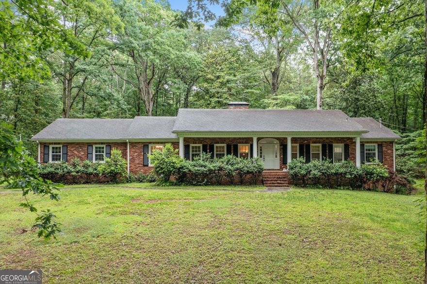 Discover one level living at its finest on a rare 3.51 acre property that includes three city lots with the potential to divide. This custom built four sided brick ranch offers space, flexibility, and opportunity.   Set in a well established neighborhood with no HOA or covenants, this home welcomes you with a wide entry foyer and fresh upgrades on the main level. Enjoy brand new luxury vinyl plank flooring, updated windows, and fresh paint throughout the main living areas. The large kitchen has white cabinets, plenty of counter space, a center island, a pantry, and a bright breakfast area.  The living area showcases a vaulted den with exposed beams. A brick fireplace stands at its heart, while custom built-in bookshelves enhance the space. The kitchen and den open up to a bright sunroom. This year-round space offers lovely views of the wooded backyard. It's great for sipping morning coffee or enjoying quiet evenings.  A formal dining room and oversized living room offer ideal space for entertaining. The owner's suite includes his and hers closets and a private bath with double vanities and a tub and shower combination. Two additional main level bedrooms share a full hall bath, offering generous space and natural light.  The finished terrace level is perfect for multigenerational living or rentals. It has its own full kitchen, a large living room with a second masonry fireplace, two additional bedrooms, and a full bath. Perfect for a teen suite or in law arrangement.  A two car kitchen level carport includes a spacious storage room for tools, gear, or hobbies. The lush 3.51 acre property is dotted with mature trees and shrubs, offering privacy and room to roam. A tennis court awaits resurfacing but could be reimagined for recreation or additional use.  This property is just minutes from I575, Historic Downtown Canton, Northside Cherokee Hospital, The Mill, and Canton Marketplace. It offers a unique blend of space, location, and potential. Divide the lots, live on one, or bring your vision to life.