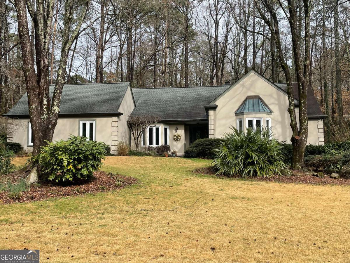 Imagine living in your own private park with a gentle stream and a waterfall behind. Enter the foyer and open stairway. To your right is the primary bedroom suite with a tall vaulted ceiling, bay windows, and enough room for a private sitting area. It features a large walk-in closet and an ensuite bath. Behind the stairway in the hall is a wet bar with easy access to the great room. Down the hall is another bedroom with a vista to the deck and yard at the back. The walk-in closet and adjacent bath make this home unusual with two bedrooms on the main floor. Wait until you see the great room! It boasts a soaring cathedral ceiling with decorative beams, tall windows, and a fireplace. There is easy access to the backyard and deck. The great room is open to the kitchen, which has a very large dining room with a bay window and open access to the great room and kitchen. The kitchen features a wonderful new cooktop with a counter making food prep easy. A new microwave and multi-function oven will help you with all your cooking needs. Generous counter and cabinet spaces, as well as an eat-in dining area, all open to the great room. There is access to the covered porch, patio, and outdoor kitchen. In the hall, the laundry room is to the right and a huge pantry to the left with access to the garage. In the garage, there is a half bath and a workroom. Upstairs, you will find two bedrooms and a bath separated by a balcony overlooking the great room with a perfect view of the artistic beams. Outside, the entertaining areas are an absolute delight. The creek which runs through the yard provides the gentle music of a babbling brook. Don't miss this home in a neighborhood with a variety of homes and prices, with the top at over two million.