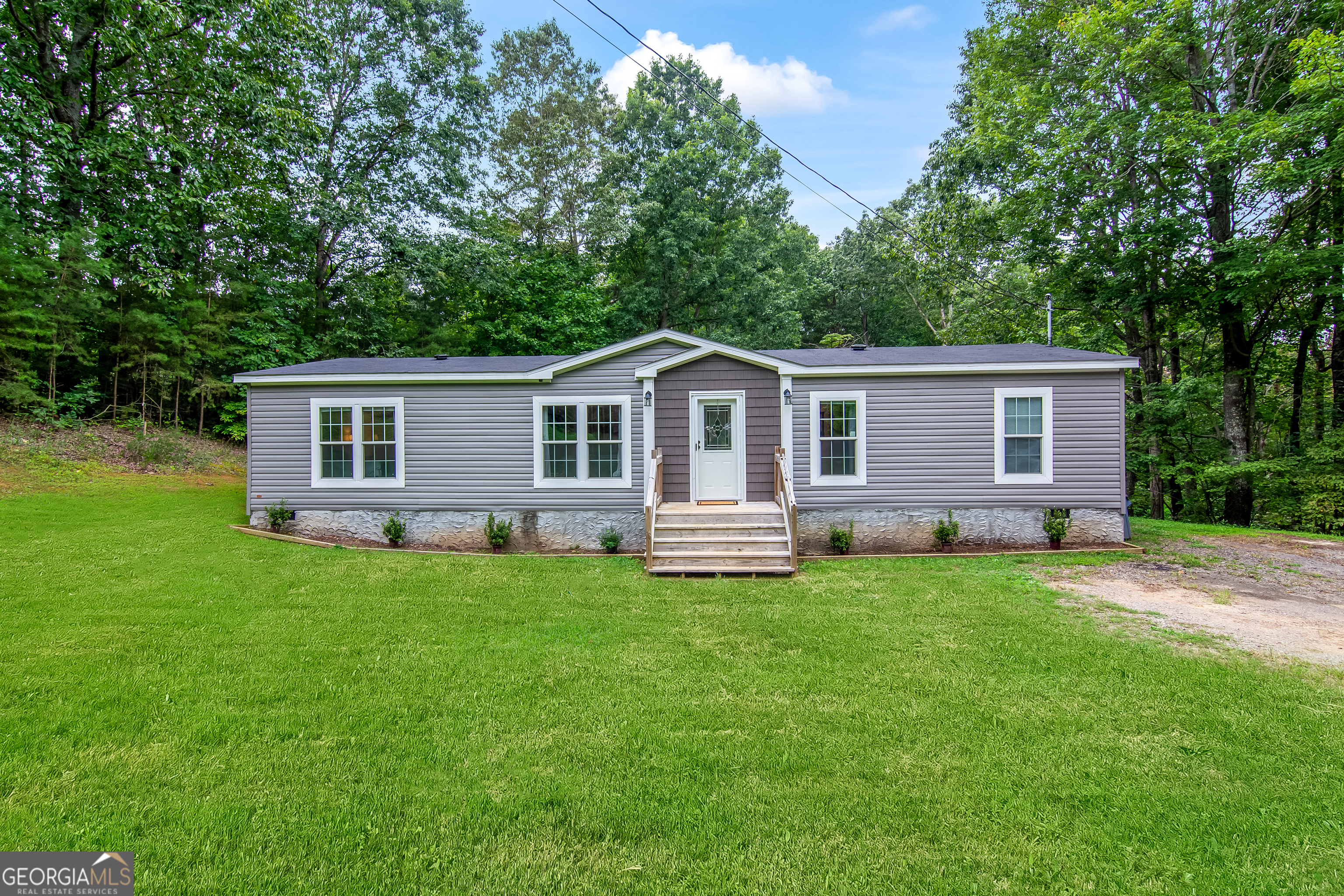 Experience refined country living in this impeccably maintained, permanent foundation, 3-bedroom, 2-bath, sole-owner residence in the heart of Ellijay, GA-offering no HOA, no restrictions, and the perfect blend of privacy and convenience. Just 8 minutes from Walmart and moments from Clear Creek Middle School, this home is tucked away on all paved roads with excellent cell service. Inside, discover numerous upgrades throughout, including underlighting in the master bathroom, elegant LVP floors, and premium finishes. The light-filled living room features a sleek electric fireplace, flowing seamlessly into a chef's kitchen with an expansive island, rich wood cabinetry, a huge walk-in pantry, abundant storage, and 2023 stainless steel appliances. The private owner's suite is a true retreat with an oversized bedroom, a huge walk-in master closet, and a spa-like bath boasting a soaking tub, double vanities with custom wood-accent mirrors, and a stunning tile-surround shower. Two additional bedrooms, a stylish guest bath, and a well-appointed laundry room with outdoor access complete the interior. Recent updates include a 2023 AC unit, hot water heater, and shingle roof, providing peace of mind and making financing easy thanks to the permanent foundation. Outside, enjoy a huge, flat, fully usable backyard beautifully enhanced with planted Green Giant trees for added privacy, along with two outbuildings-a 10 x 14 and a 10 x 20 storage shed-offering endless potential for outdoor living. This is more than a home; it's a serene retreat just minutes from town.