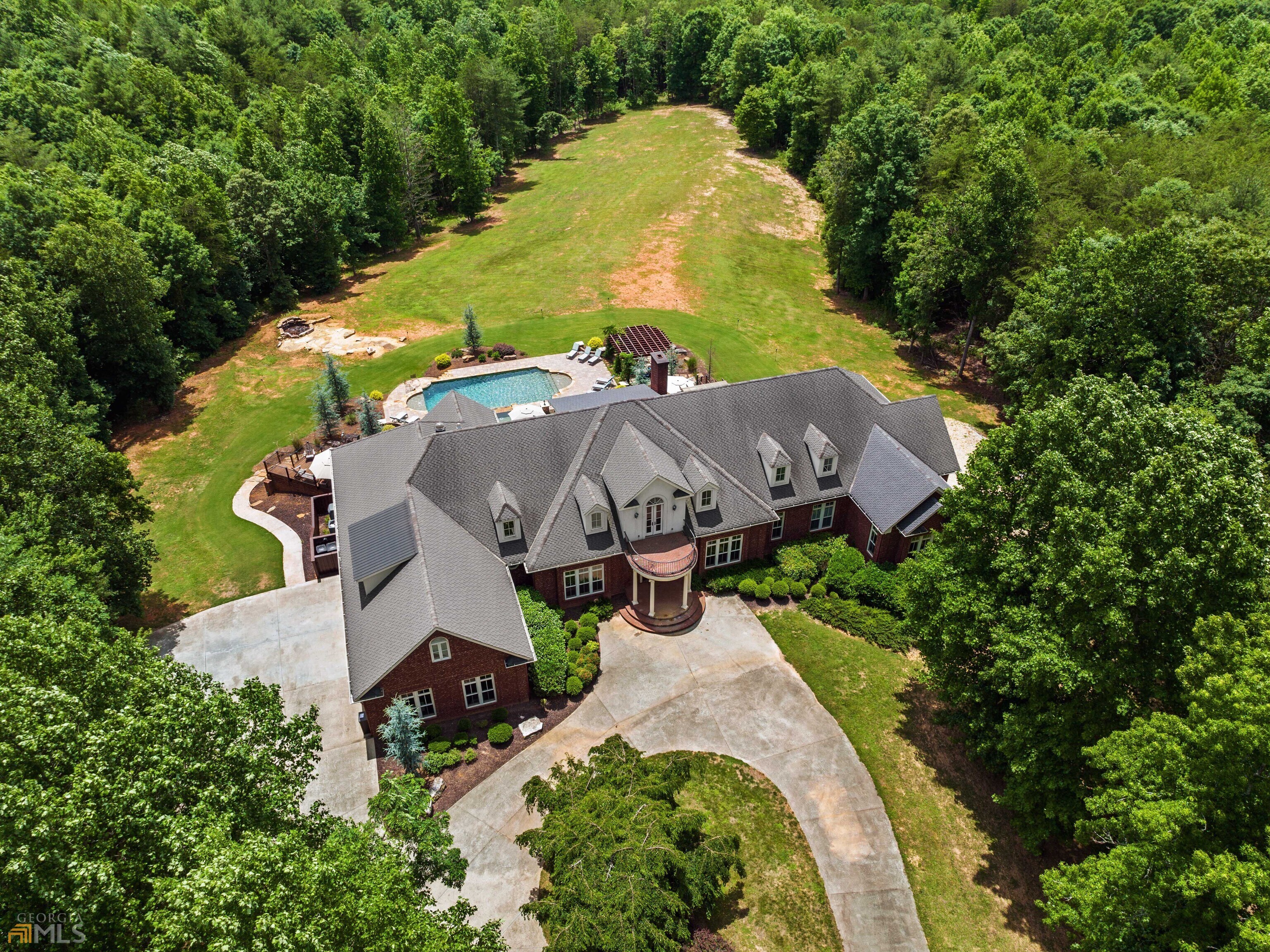 Spectacular 78 Acre Mountain Estate with 8BD, 12.5BA, 14,500 sqft Executive Home and Backyard Oasis. Perfect for groups, gatherings or entertaining on a grand scale, the home has 3 full kitchens plus a catering kitchen, 5 laundry rooms, over 5000 sqft of outdoor living space including Brazilian teak decking, hardscaped patio and veranda, plus a parking lot for 20+ vehicles. Updated kitchen has panel-front fridge, massive island with Wolf built-in top and downdraft, exotic quartz tops, prep sink, breakfast area, plus keeping room with bar and home theater. Two luxurious ownersa suites plus a third bedroom suite on the main. Two oversized bedroom suites upstairs plus game and media room. Three bedroom suites downstairs plus home gym, terrace game and media spaces, boys and girls locker rooms, and dining and living rooms. Recently installed backyard oasis has heated pool with spa and waterfall, 2 gas fire pits, pergola, outdoor living veranda, and bonfire pit. Oversized, climate controlled 3-car garage and workshop, paved drive with security gate, circular front entry drive, and separate drive and parking for terrace level. Unbeatable privacy in the heart of wooded acreage. Bonus features: elevator, 50 year architectural shingles, 2x6 walls and steel construction, foam insulated, solar hot water, plus opportunities as use as AirBNB or VRBO, weddings and events, or corporate retreats. Excellent location just minutes from The Orchard G&CC, Hwy 441, and Tallulah Falls State Park and just a short drive to Historic Clarkesville or Clayton.