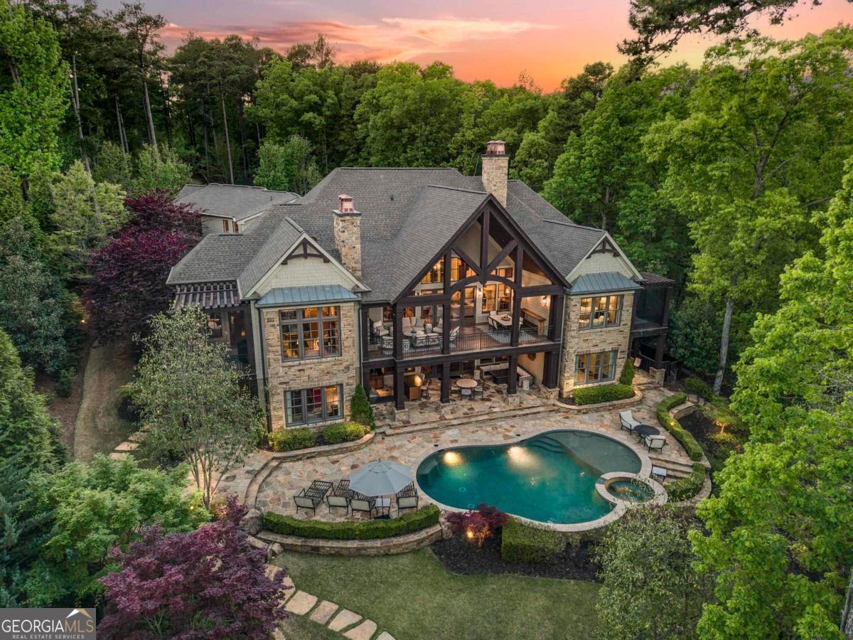 A RARE OPPORTUNITY TO OWN 4.2-ACRE LAKEFRONT ESTATE WITH OVER 500 FT OF SHORELINE IN HORSESHOE BEND AT REYNOLDS LAKE OCONEE with resort-style amenities and privacy complimented by lush grounds, creating a serene escape. This property with stunning meandering driveway and breathtaking views deliver a seamless blend of refined interiors and elevated outdoor living. The soaring great room and dining space welcome you into the main level with a statement limestone fireplace and abundant natural light. French doors anchor the room to a spacious open-air covered patio ideal for entertaining with a second fireplace and outdoor dining area overlooking the pool with a stunning lake view. The chef's kitchen features 12-foot coffered ceilings, granite countertops, custom cabinetry, and top-tier appliances by Sub-Zero, Wolf, and Miele. A keeping room with stone fireplace, breakfast nook, and lakeside screened patio invite relaxed living. Also on the main level, a nicely appointed office sits just outside the primary suite, creating a thoughtful transition into the private quarters. The primary bedroom showcases tray ceilings, dual walk-in closets, and a spa-inspired bath with a soaking tub and walk-in shower. A serene screened porch, perfect for morning coffee or taking in sunset views, extends the space with a quiet connection to the outdoors. The terrace level is thoughtfully designed for entertaining, featuring a media lounge, pool table, pub room with a 650-bottle wine cellar and tasting room, and a home gym with a convenient shower. An entertainment kitchen opens to a covered patio with a fully equipped outdoor kitchen, including a built-in grill, EVO, stone island with bar seating, gas firepit, and inviting lounge area overlooking the heated pool and hot tub. A private walkway leads to a large dock with covered boat lift. Enjoy your own nature trail in your property. Completing the interiors, the guest suite above the garage offers ample space with a sitting area/bedroom and full bath, perfect for extended visits or long term stays. Additional spaces include a walk-in pantry, powder room, laundry room, home office nook, and built-in mudroom off the 3-car garage. Whole-home audio, including invisible speakers throughout, enhance every space. Just minutes from Richland Pointe and a short boat ride to the Ritz-Carlton, it is rare to find lakefront acreage that offers both sanctuary and connection in one of Reynolds' most coveted locations. Membership available.