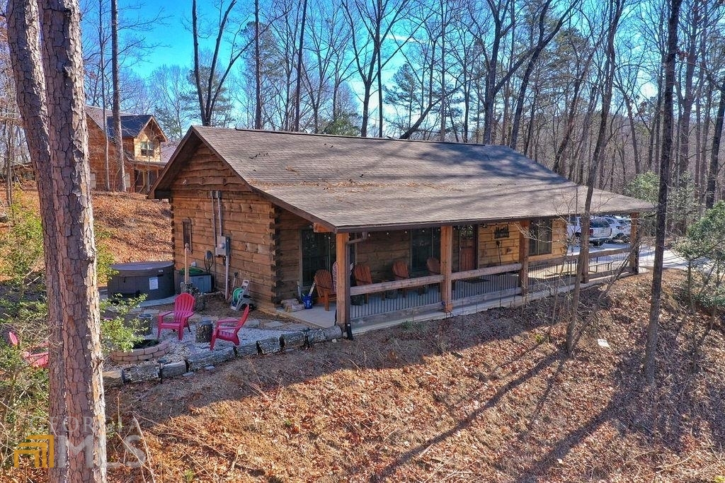 The moment you arrive at the beautiful log cabin, you will feel your stress slip away. Perched atop a wooded hill, you will find ample parking and a beautiful covered porch to welcome you. Past the porch, an AMAZING outdoor area with rustic fire pit and an inviting hot tub awaits! Inside open, cozy, and vaulted great room, kitchen with granite counters and stainless steel appliances,outdoor propane grill, a dining area that seats 6 comfortably, and a cozy living area with and a cute fireplace for warmth and ambiance when you need it! One end of the great room you will find a king BR with log bed, ceiling fan, an en-suite full bath, and a huge walk-in closet.Down the hallway on the other end of the cabin you will find another