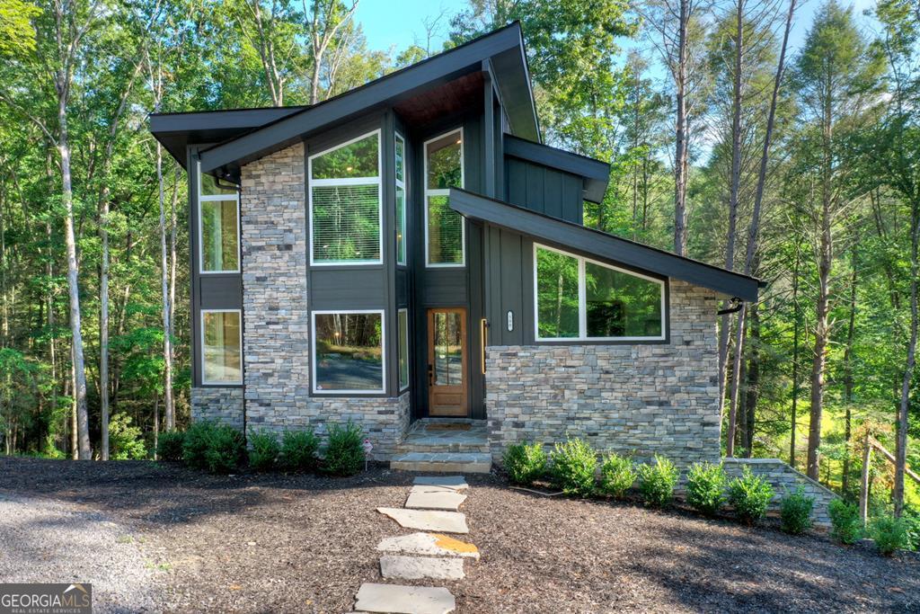 YOUR CREEK FRONT MOUNTAIN OASIS ~ This contemporary 4BR, 3.5 mountain home is nestled in the heart of the Aska Adventure Area near the Toccoa River, Lake Blue Ridge, hiking & mtn. biking trails, trophy trout fishing, thousands of U.S.F.S protected wilderness surrounding & more. Situated on 2.15 beautiful wooded acres overlooking & listening to the cascading creek frontage below totaling 565' of frontage. Custom luxury finishes throughout including gourmet kitchen, custom cabinetry, custom walk in tile showers, stainless appliances, custom lighting & plumbing fixtures & more. All BR's are ensuites w/ upstairs ensuite featuring add. Sitting/office area. Open easy living floor plan that features large island/bar in kitchen offering workspace & seating great for entertaining. Soaring cathedral ceilings throughout w/ lots of glass & windows allowing you to enjoy the great outdoors. Modern style gas log fireplace in the main level living room & in basement Rec Rm/Den in addition to outdoor fireplace on porch overlooking this picture perfect setting. Two levels of covered porches on front of home w/ terrace level porch featuring hot tub & sauna. Finished basement features additional living quarters with 2 BR's & BA with Rec Rm/Den & complete custom wet bar that is a show stopper! Great location for future garage w/ lots of parking on all paved road frontage