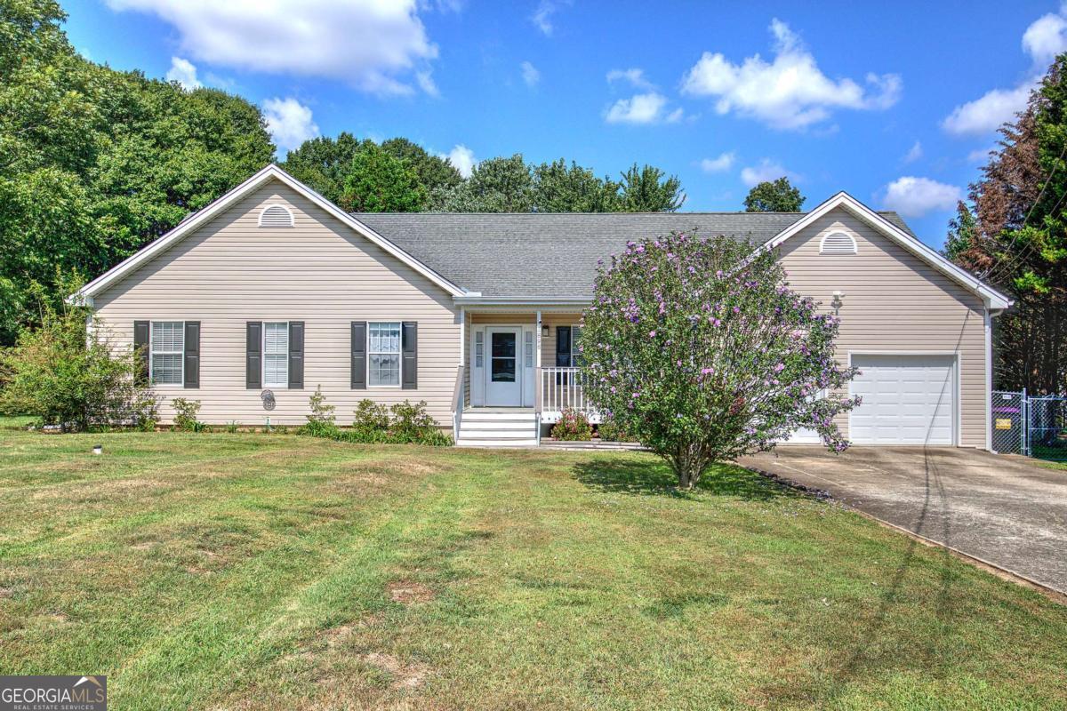 Welcome home to 1896 Bullard Road, a beautifully designed ranch-style residence that combines charm, comfort, and functionality all on one level. The inviting front porch, framed with durable vinyl siding, sets the tone for a home that is both welcoming and low-maintenance. As you step through the foyer, you're greeted by a formal dining room that flows seamlessly into the expansive living room. Here, a striking rock fireplace serves as the centerpiece, while soaring vaulted ceilings and luxury vinyl plank flooring create an open, airy feel. Natural light pours in through French doors, offering a picturesque view of the private backyard and extending the living space outdoors. The kitchen is thoughtfully designed for both everyday living and entertaining, featuring solid surface countertops, stainless steel appliances, a stylish tiled backsplash, and a generous island that provides extra seating and workspace. Rich stained cabinets add warmth, while tiled floors and a walk-in pantry ensure both beauty and practicality. A cozy breakfast area offers the perfect spot for morning coffee. Just steps away, a large laundry room adds convenience and functionality to the home's layout. The primary suite is a true retreat, with vaulted tray ceilings that elevate the space and LVP flooring that continues the home's modern, cohesive look. The owner's en-suite bathroom is appointed with a double vanity enhanced by sleek modern hardware, a relaxing garden tub, a beautifully tiled shower, and a spacious walk-in closet. The secondary bathroom is equally well-finished, featuring a solid stone countertop and thoughtful design details. Out back, a deck extends your living space into the outdoors, ideal for grilling, entertaining, or simply unwinding. The backyard is level and fully fenced, providing both privacy and versatility for play, pets, or gardening. This home truly offers a seamless blend of style, comfort, and convenience in a setting designed for everyday living.