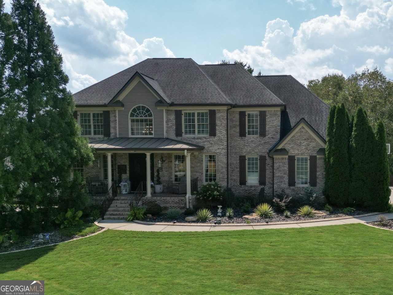 Stunning three-sided brick two-story home with a finished terrace level in the highly desirable area just south of Hickory Flat , featuring hardwood floors throughout, a welcoming rocking front porch, two-story foyer, separate office, dining room, and spacious Family room. The gourmet kitchen with custom cabinets and quartz countertops, large island, and elegant finishes designed for both cooking and entertaining. The master bedroom retreat offers comfort and privacy, additional three spacious secondary bedrooms upstairs, including one with its own private bath while the other two share a Jack-and-Jill bath. Terrace level provides additional living space, full bathroom and a private sauna. Outdoor living is exceptional with a fenced backyard, swimming pool with saltwater system , covered stone-stacked patio, outdoor kitchen, and wood-fired pizza oven. A three-car garage completes this home, ideally located in one of Woodstock's most desirable areas.