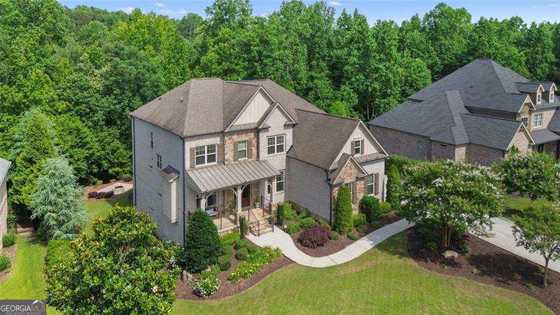 Beautiful custom-built home with a timeless brick and stone exterior in the highly desirable gated community of Manor North. This expansive home is an entertainers' dream featuring 6 bedrooms, 5 full bathrooms and a 3-car garage. Enter from the stacked stone porch through the 8-foot double front doors past the large formal dining room and living room with fireplace. The floor plan opens to a 2-story family room with beamed ceiling, fireplace, expansive bay of windows and built-in bookcases. There is also a bar area and circling back to the dining room a butler's pantry. The kitchen has a walk-in pantry, large island with cookbook storage on both ends, pull out cabinet drawers, double ovens and a professional 6 burner gas range. Open to the kitchen is a breakfast area with 3 walls of windows or doors that puts you in mind of a tree house. Outside is a large deck equipped with a gas grill overlooking the lush, private backyard. The main level also includes a guest suite or office and a guest bath and a mudroom leading out to the garage. Upstairs features the private master suite with coffered ceiling, ensuite bathroom with double sinks, soaking tub and walk in shower, a huge walk in closet and secondary closet. In addition, there are 2 bedrooms with a full hall bath, and an oversize 4th bedroom with an ensuite bath. The laundry room is also upstairs convenient to the bedrooms. The terrace level is finished with a media room, rec room, large gym, office or bedroom, full bath with walk in shower, custom bar area with ice maker and wine refrigerator and large storage area. Outside there is a large, covered patio under the deck and breakfast room. The backyard also features a large firepit area. Top ranked schools, shopping and dining only minutes away, this active community features a large clubhouse, Olympic and kiddie pools, 4 pickleball courts, 3 tennis courts and lower Cherokee county taxes.