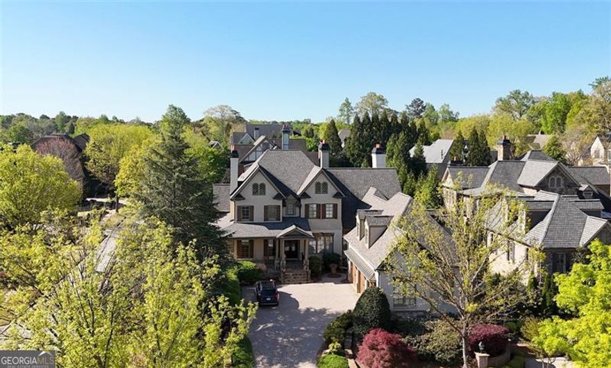 Exquisitely perched on a premier corner lot, this exceptional painted brick and stone traditional craftsman commands a presence in one of East Cobb's most exclusive enclaves of homes.  The wrap around porch welcomes you into a stately foyer with exquisite triple crown molding and 12 foot ceilings.  The wood paneled study features a fireplace, coffered ceilings, and built-in storage.  The dining room seats 12+ guests and features exquisite millwork on the ceilings and walls.  Bathed in light, the living room with coffered ceiling and custom stone fireplace opens to the deck overlooking the pool.  Built for entertaining, the chef's kitchen features Wolf and Sub-Zero appliances and opens to a dramatic keeping room with beamed tongue and groove cathedral ceiling and cozy fireplace.  The spacious master on the main suite features triple tray ceilings and stunning bath with free standing copper tub, marble flooring, dual vanities, dual water closets, and two enormous walk-in closets.  Upstairs are four large en suite secondary bedrooms, two with attached living space that would be perfect for an office or playroom.  The expansive, walk out terrace level is the ultimate fun zone with bar, game room, theatre and living room that opens to the exceptional hardscaped patio and pool.  The terrace level also includes an exercise room, bedroom and full bath.  The backyard oasis will delight with heated salt water gunite pool, complete with waterfall, spa, and lush landscaping.  HOA provides landscaping and yard maintenance. A private well supplies water for the pool and irrigation systems, saving hundreds of dollars a month. This phenomenal home is located in the award-winning Mount Bethel/Dickerson/Walton school districts.