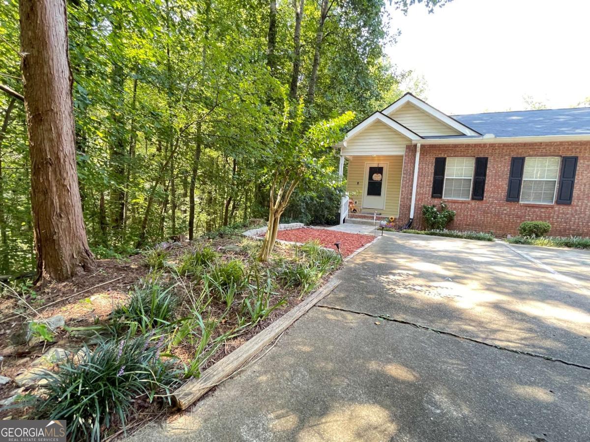 Beautiful serene setting end unit condo in the wooded Hidden Hollow Community. Brick front with covered front porch and new landscaping design. This updated open floor plan condo has a great feel with a welcoming foyer and open floor plan fireside great room. All new flooring, kitchen with new stainless steel appliances, updated bathroom with tile floor, new vanity and shiplap accent wall, new LED lighting, and wow, take a look at the great room ceiling fan. Primary suite is at the back with a large vanity and walk in closet. Front bedroom has private access to a really pretty updated bath and double seasonal closets. Tons of storage with pull down attic stairs, hall closet, large laundry room, storage building on deck and a tall walk in crawlspace. Back patio door opens onto spacious deck overlooking a huge forest and law. But don't worry - the HOA maintains the lawn and exterior. New deck coming in two weeks. True to the name of Hidden Hollow, this is one of the best locations for privacy with just the one building surrounded by woods and hidden on a long driveway. Quiet neighbors. There is a babbling creek flowing next to the property and under the road. Hidden Hollow is a great community for walking and enjoying nature. Wonderful HOA and covers all exterior grounds and anything outside the structure including roof, gutters, decks, city water included and maintains septic system. Owner needs only interior insurance.