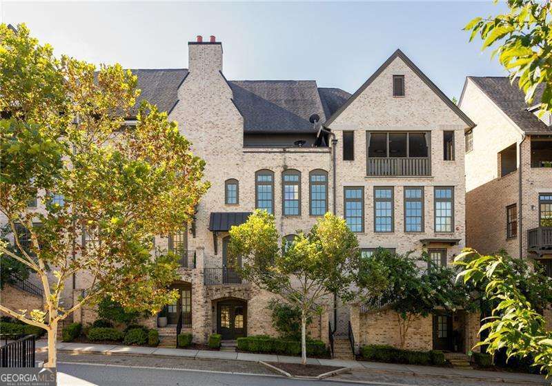 Welcome to the luxurious Aria community! This fantastic 4-story townhome features the Nabucco floorplan which includes an elevator with access to all four levels, 3 bedrooms, and 3 1/2 baths, and is full of custom upgrades that truly make it one of a kind. Some of the many features include hardwood flooring throughout, recessed lighting, built-in cabinets with a wine cooler, surround sound prewired in the living room and primary bedroom, upgraded bathroom mirrors, smart toilet seats, and thoughtful additions that make all the space throughout the home extremely well utilized. Step into the 2nd level foyer and to the right enter a bedroom with an ensuite with a walk-in closet and a private full bathroom. This bath has stone countertops, tile flooring, and a tiled shower. Moving down the hall is a large hall closet, built-in cabinetry with a coat rack, and storage. Adjacent to this area is the laundry room with a utility sink. Access to the spacious two-car garage complete with storage shelving is on this level, as well as the elevator and a large storage closet. As you walk upstairs, you will delight in the open floor plan of this 24-foot-wide home providing ample space for a large dining table at the front, and an expansive kitchen in the center. The dining area is filled with light from the front windows. The kitchen has stainless steel appliances, a 5-burner gas cooktop with a vented hood, and white cabinets. The expansive center island with under-cabinet storage will accommodate 6 bar stools and boasts 5 cabinets under the island for plenty of storage and a wine cooler. Gorgeous white/gray veined quartz countertops and gray tile make this the perfect spot to gather. You may prefer to cozy up to the fireplace in the family room with its stunning custom built-in cabinetry on either side as well as a wine cooler. This room is bathed in sunlight by windows across the back and sides of the room. The glass patio door opens to the private deck which is ideal for grilling or enjoying the outdoors. Continuing up to the top level is a completely private retreat. At the top of the stairs is a wet bar with a wine cooler, sink, built-in cabinetry, and tile backsplash. There is a relaxing outdoor sitting area with a folding glass door. This is a great place to pause and enjoy the end of the day and beautiful sunsets overlooking the community. As you enter the primary suite, you will find a trey ceiling, and a spacious bedroom flooded with natural light from floor-to-ceiling windows. Relax in the primary bath that has 2 beautiful gray shaker cabinets, a freestanding tub, a walk-in shower with a rainwater showerhead, exquisite quartz countertops, and a large custom walk-in closet. Finally, an adjacent laundry room makes this space complete. At the lower level of this home, there is a third bedroom. Could also be ideal for a home office, or an in-law suite. This magnificent space has a large bar area equipped with a large undermount sink, dishwasher, microwave, and small refrigerator. In addition, there is a full bathroom with tile flooring and shower, and a large closet. There is also another entry door on this level providing private access if desired. Just outside of the suite is a full-sized wall of storage and shelving, perfect for a study or reading room. Come to Experience Aria a "Live, work, play" community in the heart of Sandy Springs. Aria North amenities include two pools, a clubhouse, a fitness center, and a 12-acre park with walking trails. Enjoy restaurants, shops, and local businesses just mins away. Ideal location with immediate access to GA400, I285, Perimeter Mall, and Sandy Springs City Center.