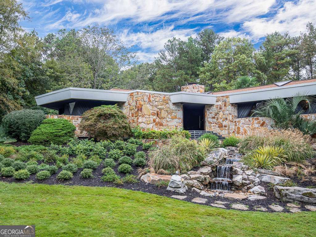 Designed by renowned architect Robert Green, an apprentice of the world famous architect Frank Lloyd Wright. This breathtaking estate is a masterpiece of art and architecture, seamlessly blending modern luxury with natural elements to create an exclusive and private retreat. Move-in ready and meticulously restored, this home is designed for the discerning buyer who appreciates fine design, grand entertaining, and curated living spaces. The gourmet kitchen, outfitted with Miele gas appliances, a built-in coffee maker, double dishwashers, and a waterfall stone island, is perfect for hosting lavish dinners and intimate gatherings. The expansive living areas feature rustic stone walls, a striking natural stone fireplace, a wood-paneled ceiling with pendant lighting, and custom-built glass pivot doors, allowing guests to seamlessly transition from one stunning space to another. The master suite is a sanctuary of indulgence, offering a steam shower, jetted Jacuzzi tub with skylight views, and a separate Zen tub room. A temperature-controlled wine storage room, leading to a private patio, enhances the home's entertainment appeal. The finished basement provides a stylish entertainment lounge and bonus room, perfect for gallery-style exhibits or immersive experiences. This smart home features a central control panel, built-in sound system, and seamless indoor-outdoor connectivity, making it effortless to set the perfect ambiance for any event. Outdoors, the gated and fully fenced estate is an entertainer's paradise, boasting a heated saltwater pool, a full outdoor kitchen with a Big Green Egg smoker, ice maker, and waterproof big-screen TV, an inground trampoline, and manicured grounds designed for hosting unforgettable soirees. With breathtaking views from every room, this residence is an architectural work of art, offering a sophisticated lifestyle for the elite entertainer and art connoisseur. Schedule a private viewing today to experience this unparalleled masterpiece.