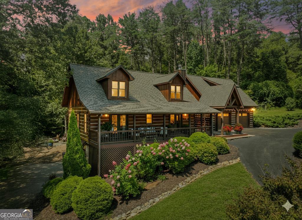 This stunning 3BR/3BA luxury log cabin is the perfect blend of modern rustic elegance and mountain charm, just 5 minutes from downtown Blue Ridge and steps from Lake Blue Ridge. Set on a level, beautifully landscaped lot with exceptional curb appeal, the home features paved access, a circular driveway, and an oversized 2-car garage with a fully finished guest suite above. Between the garage and main home, enjoy a cozy veranda ideal for outdoor entertaining, complete with seating and an inviting fire pit area. Inside, the newly renovated interior boasts soaring natural light, a gourmet kitchen with quartz countertops, a large island, and stylish finishes throughout. The main level includes a king suite with double vanities and a soaking tub, plus a queen suite for guests. Upstairs, a spacious loft provides additional living or sleeping space. The semi-finished basement is stubbed for an extra bathroom and can easily accommodate a bedroom, game room, or home theater. Featuring log chinking for authentic character, this home offers both timeless appeal and modern convenience with a newer roof and HVAC. If you are looking for a charming cabin retreat, this turnkey property is a rare gem in one of Blue Ridge's most sought-after neighborhood.