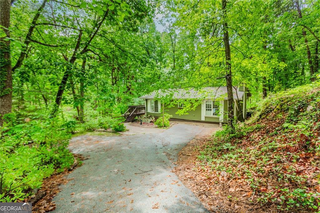 Have you been dreaming of owning a house on a lake? Well here is your opportunity! This private and quaint cottage on Lake Lanier is ready to welcome you home. You will have the best of both worlds here - surrounded by nature you feel like you are in the mountains AND you have access to the lake from your very own permitted platform dock. Imagine spending time in the hot tub or grilling from the expansive deck, overlooking the lush tree filled property with seasonal lake views. You will enjoy exploring the large lot (.69 acres) with water features, as you make your way down the path and over a couple of small bridges to the dock. Grab your canoe or kayak, as this is a great cove to begin your adventures out into the lake. The cottage itself is so inviting - windows galore and french doors that lead you into the open living room and kitchen. The wood planked cathedral ceiling sets the tone for the character of this space. The kitchen has stainless appliances and granite countertops. Convenient pantry/laundry room. The guest bathroom features an updated new shower. The master is a retreat with its own fireplace, large closet, and ensuite bathroom with jacuzzi style tub. A lower deck leads you to a small unfinished basement, great for extra storage. Lastly there is room for parking at the front of home and additional off street parking up top. Check out the video tour. You really don't want to miss this one! Convenient to 400, Dawsonville, Gainesville. North Forsyth school district.