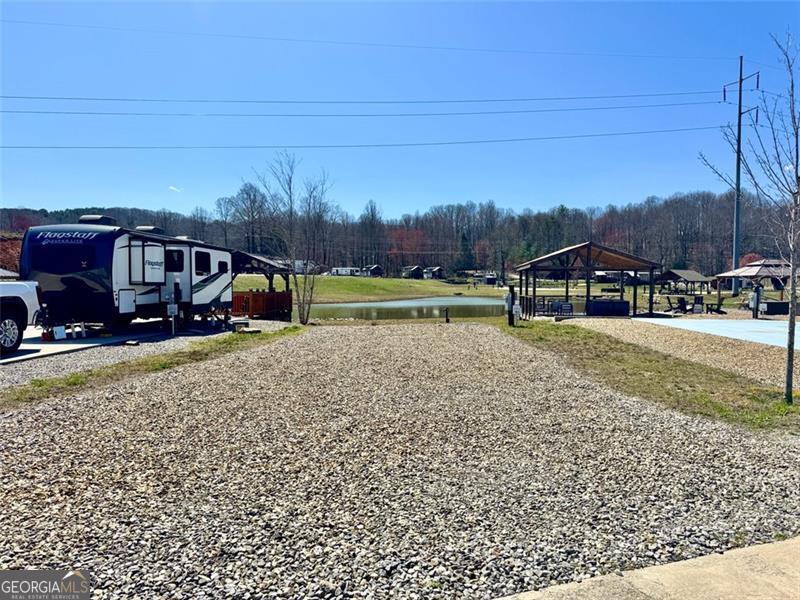 Nestled within a secure, gated community, this pond-side gravel RV lot offers you the chance to create your ideal mountain haven. Whether you're seeking a peaceful escape, an investment opportunity, or a place to call home, this site is the canvas upon which you can craft your ideal mountain lifestyle. This spacious lot is perfect for your RV or a charming tiny home. The choice is yours! You can also use it as a full-time residence or rent it out to fellow adventurers seeking their own mountain retreat short or long term. Unleash your creativity and customize this lot to your heart's content. Imagine crafting the perfect outdoor oasis, complete with a cozy campfire pit, lush landscaping, and a deck with breathtaking sunset views. Community Amenities: You won't find a shortage of activities within this vibrant community. Dive into the sparkling pool on hot summer days, host gatherings at the community pavilion or at the clubhouse (equipped with laundry and a kitchen, and showers). Your furry friend will adore the on-site dog park. There is a playground and a Gaga ball pit-endless fun for all ages. Stay active with a game of basketball, pickleball, or disc golf. And don't forget to relax by one of the community fire pits as you make new friends and share stories of your mountain adventures. For those who love water adventures, boat and RV storage is conveniently available on site, ensuring your equipment is secure and ready for your next expedition. Beyond the community, you'll find a treasure trove of activities just moments away. Explore the region's wineries, orchards, and hiking trails-each offering a unique taste of the North Georgia Mountains. State parks are a stone's throw away for outdoor enthusiasts, and Lake Blue Ridge is just 2 miles down the road for boating, fishing, and water sports. The charming downtown of Blue Ridge, GA is a short drive away, where you can enjoy quaint shops, delightful dining, and a welcoming community atmosphere. Whether you seek adventure, relaxation, or a combination of both, this RV/tiny home lot in the North Georgia Mountains is your gateway to it all. Embrace the mountain lifestyle you've always dreamed of, surrounded by breathtaking natural beauty and a warm, welcoming community. Don't miss out on this extraordinary opportunity - schedule your visit today and let the mountains call you home!