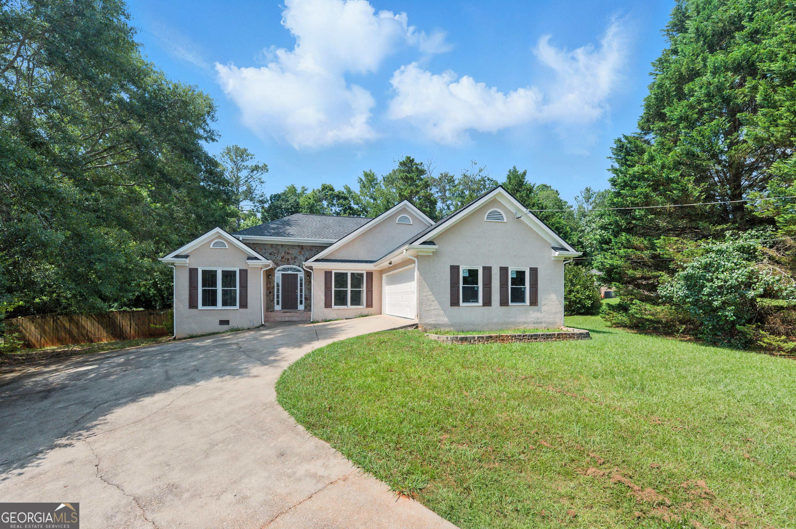Tucked away on a picturesque lot with a long, winding driveway, this European-style stucco home with elegant stone accents offers a warm welcome the moment you arrive. The side-entry garage keeps your curb appeal clean and classic while adding convenience and privacy. Step inside and be greeted by a sun-drenched, single-level layout that blends style and functionality. The inviting foyer opens to a formal dining room - perfect for hosting holidays and memorable gatherings - while the spacious great room straight ahead steals the show with its soaring vaulted ceiling and cozy stone fireplace, creating the ideal setting for relaxing evenings or lively conversation. The kitchen features timeless white cabinetry, a built-in breakfast area for casual dining, and extra cabinetry to make organization effortless. Whether you're whipping up a weeknight dinner or entertaining, this kitchen has the space and flow to support your lifestyle. The spacious owner's suite is a peaceful retreat with elegant tray ceilings and an ensuite bath that feels like a spa - with a separate shower and a luxurious soaking tub to melt the day away. Step outside onto the deck that overlooks a large, level backyard - ideal for summer barbecues, family games, or a pool installation. A dedicated storage shed keeps your tools and toys tucked away so you can enjoy your outdoor space clutter-free. Freshly painted in a soothing neutral palette, this move-in-ready home is your blank canvas to make it uniquely yours. A rare blend of charm, space, and practicality.