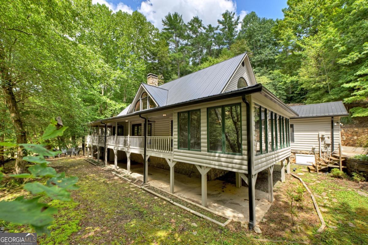 Spectacular River Frontage on the CARTECAY RIVER overlooking Blackberry Falls! This 2.56-ACRE RIVERFRONT ESTATE offers the rare opportunity to own a true River Lodge on the ever popular "SHOALS",where the whitewater rapids of the Cartecay River meets exposed rock formations, creating mini-rapids and beautifulsounds of rushing water. This property is an ideal spot for relaxing by the water or enjoying kayaking and tubing over the falls. ***This is a special property indeed with no HOA, all paved roads and less than 5 miles from town.*** Inside, an open-concept design welcomes you with soaring cathedral ceilings, custom wood accents, built-in bookcases, and a gorgeous stone wood-burning fireplace. The spacious kitchen features abundant cabinetry, walk-in pantry, stainless appliances, and seamless flow to the dining area and sunroom, perfect for enjoying the views and sounds of the river. The luxurious oversized primary suite includes a steam shower, jetted tub, and private retreat space while the upper level offers two expansive guest suites, 2 half baths and a joint spa-like bathroom. (Upstairs banister handcarved and imported from Sweden.) Enjoy the outdoors from the all-NEW PARTY PORCH overlooking the falls, a new FIREPIT along the river's edge, or the wraparound covered porches. Upgrades include NEW: metal roof, exterior paint, lighting & fans, Generac whole-house generator, refrigerator, dishwasher & garage door system. There is also a stunning custom stone entry wall, koi pond, and level yard with easy river access. Additional features: 2-car garage, gated entry, paved roads, public utilities, hi-speed internet, and no HOA fees. Less than 5 miles from Downtown Ellijay, this home is privately tucked away yet close to shopping, dining, and wineries. Flood insurance not required. This home has never been a vacation rental; however, STR's are allowed.