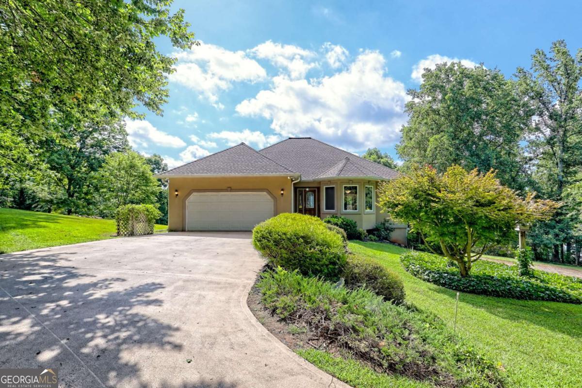Spacious 3-bedroom, 2.5-bath home poised on 1.94 acres of unrestricted land, boasting long-range mountain and Lake Chatuge views from both levels. The kitchen features stainless steel appliances, white cabinetry, granite countertops with complementing tile backsplash, gas surface cooktop, wall oven, pantry, and a breakfast nook. Enjoy your meals in the dining room or step outside to the covered rear deck, where you can enjoy the scenery. Relax in the family room, which features a stacked stone fireplace and large windows that allow for plenty of natural light. The main-level primary suite includes a whirlpool tub, a tiled shower, walk-in closet, and private access to a covered deck. The lower level features a large family room with a wood-burning stove and wet bar, two additional bedrooms with a full bath, and patio access for more views. Convenience is key with two driveways, one that accesses the main-level 2-car garage and another that leads to the lower level. Set in beautifully landscaped yard, the property also includes a fire pit area. With a roof only four years old and plenty of outdoor space, this home is an inviting retreat with nearby boat ramps, hiking trails, and local fare of Hayesville or Hiawassee. Ideal for those seeking space and scenic beauty!