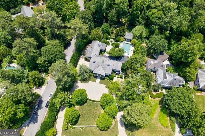 This beautifully maintained Norman Askins redesigned home in prestigious Buckhead is both practical for everyday living and unmatched in elegance. The spacious family kitchen is adjacent to the sunny great room. French doors lead to the luxurious outside pool area, offering generous covered seating and dining space. The main floor primary wing features dual well-appointed and newly decorated dual bathrooms, with marble showers and generous closets. The spacious primary bedroom includes a fireplace, custom moldings, French doors and a sun/sitting room overlooking a lovely, curated garden that leads to parkland with a stream at the foot of the garden. The second floor has four generous bedrooms, three full baths, and an additional sitting/TV room. The home is flooded with natural light thanks to its large windows, creating a spacious and bright atmosphere throughout. The garden/lower level includes a party kitchen and dining area, a beautifully well-designed wine cellar, and a family room. An extra bedroom with bath, and designated exercise room with a bathroom make this area perfect for grandparents or a guest suite on the garden level. Tucked away with its own patio leading to the garden is a generous and practical office, ideal for working from home. The beautifully manicured grounds feature a formal English garden and a covered pavilion overlooking the saltwater pool and offer a lovely woodland view. Enjoy entertaining on the large Pennsylvania bluestone terrace overlooking the serene and wooded landscape. Truly, this is a special home on 1.72+/- acres in Tuxedo Park!