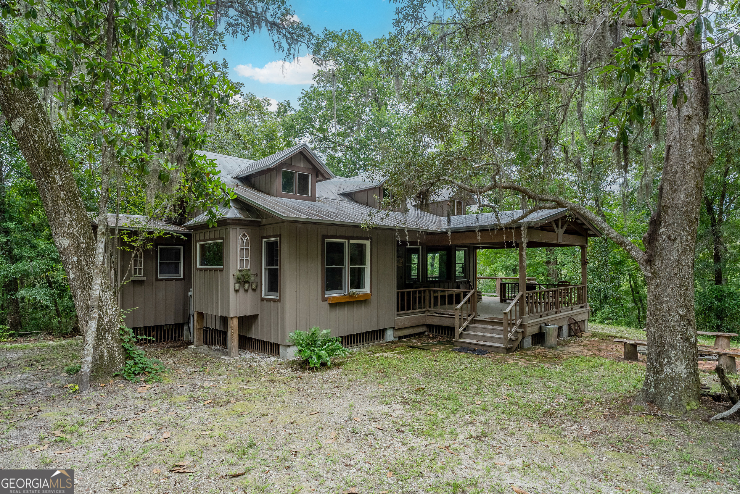 Discover Your Private Paradise Just 45 Minutes from North Jacksonville! Perched atop a scenic 52-foot bluff, this stunning 12.9-acre retreat offers the perfect blend of seclusion, natural beauty, and outdoor adventure. Located just 45 minutes from North Jacksonville and the airport-and within easy reach of the breathtaking beaches of St. Simons, Jekyll Island, and Amelia Island-this property is your gateway to coastal relaxation and exploration. The heart of the property is a fully remodeled 1,500 sq ft cabin featuring 2 bedrooms and 2 bathrooms, with vaulted wood ceilings and expansive windows that bring the outdoors in. Step outside to enjoy three versatile pole barns, a large covered front porch, and a spacious side deck-perfect for entertaining or simply taking in the quiet surroundings. A cozy bricked fire pit provides the ideal setting for morning coffee or sunset views. Additional amenities include a whole-house generator, private well, and a custom outdoor cooking area with underground propane-designed for year-round comfort and convenience. The larger pole barn has large locking barn doors for storing a boat or parking a buggy securely. It is also set up with running water and LED lighting, and a large stainless-steel table for cleaning fish or butchering game. There is also a game skinning section with a gambrel on pulleys with lighting and running water. As part of the HOA, you'll also enjoy access to over 200 acres of shared land for hunting, fishing, hiking, and exploring scenic trails, including private access to the river and secluded white sand bars along the Satilla River. This property boasts 531 feet of direct river frontage, adding even more value to your outdoor lifestyle and providing unmatched access to the natural beauty of the Satilla River. This rare find offers the perfect balance of privacy, comfort, and adventure, with easy access to Georgia's most beautiful beaches and waterways. Whether you're searching for a peaceful retreat or an outdoor recreation hub, this property delivers the best of both worlds.