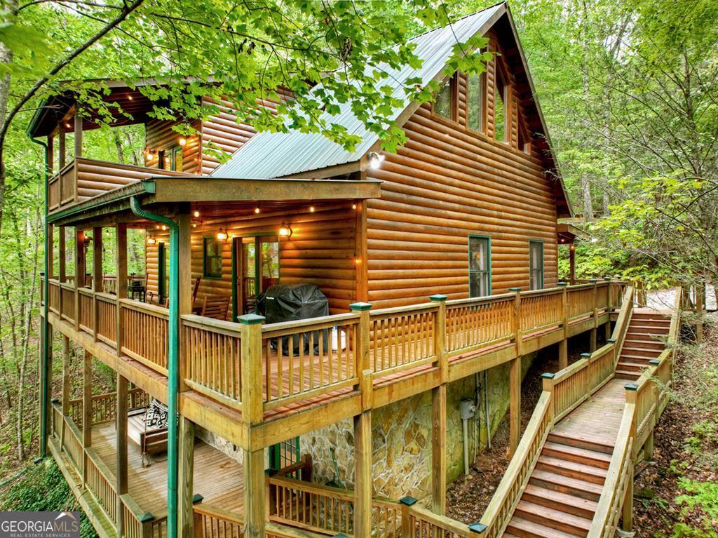^HANDCRAFTED MOUNTAIN CABIN LIVING^ This 3BR, 3BA log sided cabin feels nestled in the great outdoors w/ lots of privacy situated on this x acre beautiful wooded lot. The vibrance of this mountain sanctuary is obvious from first look as you enter this open floor plan design that features custom pine green kitchen cabinets w/ granite countertops & updated stainless steel appliances. Soaring cathedral ceilings, lots of windows & fixed glass, exposed beams, and floor to ceiling grand rock gas log fireplace adds to the warmth of the great room. Each level provides lots of privacy having a BR/BA on each level for a total of 2.5 stories in this chalet inspired design. Finished terrace level offers great entertaining space w/ a large Rec Rm/Den & a BR, BA & storage area opening onto terrace level covered porch. 2nd floor primary ensuite features a reading loft + private balcony or "treehouse" offering a great place to reconnect w/ a glass of wine at the end of the day. Main level offers great outdoor living spaces w/ wrap around covered porches + detached "outdoor party pavilion" offers the best in outdoor living featuring a oversized hot tub, TV/outdoor living furniture & entertainment space - This is what it's all about. Circular driveway offers plenty of parking & easy access. Located near the Chattahoochee-Oconee National Forest, trophy trout fishing waters, Lake Blue Ridge & centrally located between Blue Ridge & McCaysville. This property may be purchased turn key fully furnished - Furniture, decor, accessories to be purchased separately via a Bill of Sale. This cabin has been a short term rental (STR) - Prime investment property!