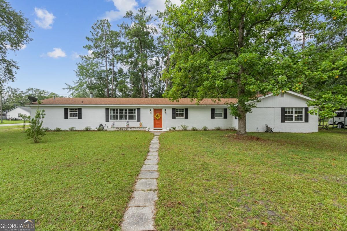 Welcome to 73 Azalea Avenue in Folkston, GA! Nestled on a spacious corner lot that includes the neighboring parcel for a total of 0.68 acres, this beautifully updated home offers room to live, work, and play-all with NO HOA restrictions. The main house features 4 bedrooms and 2.5 bathrooms, including a generous primary suite with a large walk-in closet and an en suite bathroom boasting a soaking tub and separate tiled shower. You'll love gathering in the cozy living room with a fireplace, enjoying meals in the large dining area, and cooking in the updated kitchen featuring stainless steel appliances, subway tile backsplash, and quartz countertops. Need space for guests, hobbies, or a home office? A detached studio-style building provides a flexible space with a half bath and a pre-installed shower (shower not currently connected to water)-perfect for future expansion. This building also includes a separate workshop area, ideal for tools, storage, or creative projects. Enjoy outdoor living with ample yard space and a large screened-in porch. Located just minutes from downtown Folkston. Don't miss your chance to own this versatile property with room to grow and no HOA limitations-schedule your showing today!