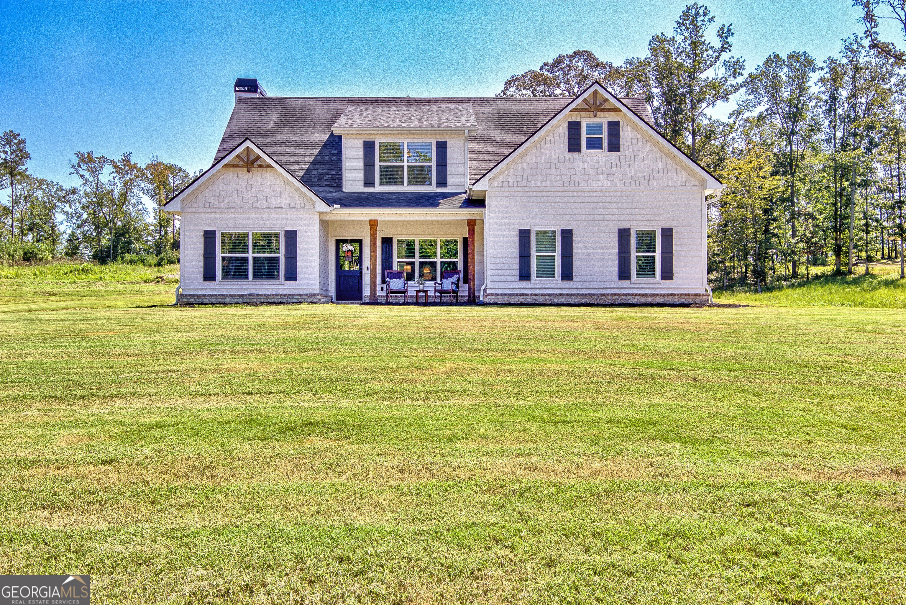 Welcome to this stunning Trademark-built Smithfield floor plan home, nestled on 5 acres just minutes from Downtown Newnan and convenient to I-85. This immaculately maintained property offers 4 bedrooms, 3 full bathrooms, and a bonus room. Step inside to find a spacious dining room that can easily flex as a home office or playroom, as well as a secondary bedroom and full bath on the main level-ideal for guests. The open-concept living area features beautiful luxury vinyl plank flooring and a cozy living room with a gorgeous brick fireplace. The chef's kitchen is a true gem with quartz countertops, a tile backsplash, a large island with seating, a white porcelain farmhouse apron sink, and stainless steel appliances. The adjacent eat-in kitchen space is perfect for casual dining and entertaining. The main-level primary suite offers a peaceful retreat with an en-suite bathroom, 2 walk-in closets, one with direct access to the laundry room for ultimate convenience. On the second floor, you'll find two additional bedrooms, a full bath, and a generously sized bonus room-ideal as a media room, workout space, or additional living area. Enjoy quiet mornings and peaceful evenings from your covered back patio, where you can take in breathtaking sunrise and sunset views plus you might catch a wildlife sighting. Additional features include: AT&T Fiber Internet, an oversized parking pad and two water heaters. Don't miss the opportunity to own your own private oasis with modern conveniences and timeless charm-all just a short drive from city amenities. Please note that GPS will take you to the street over.