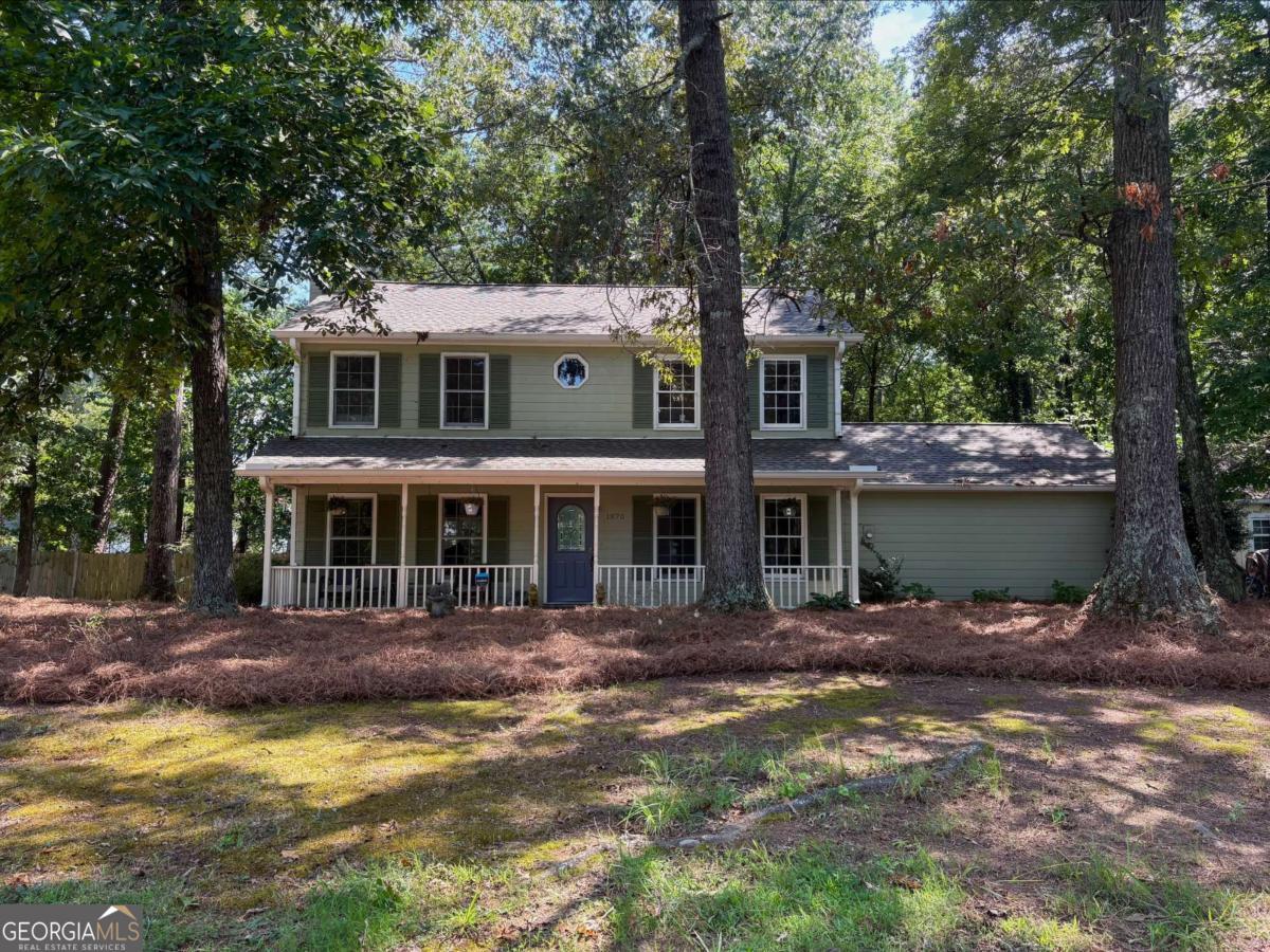 This charming 3-bedroom, 2.5-bath residence offers 1,850 square feet of inviting living space filled with natural light and timeless details. Enjoy your mornings on the covered front patio, complete with classic wooden balusters, an ideal spot to sit and relax rain or shine. Step inside to a spacious living room with a gorgeous marble fireplace, flowing seamlessly into a cozy sunroom with built-in cabinetry, perfect for reading, entertaining, or simply unwinding. The country-style kitchen features stainless steel appliances, a wooden island, a walk-in pantry, and a lovely breakfast area that overlooks the backyard. A formal dining room provides the perfect setting for hosting guests, while the two-car garage offers direct access and remote-controlled doors for convenience. Out back, you'll find a peaceful and private yard with a generous wood deck, perfect for outdoor dining and gatherings. Two sheds offer plenty of extra storage. Upstairs, the owner's suite is a true retreat, complete with hardwood floors, a second marble fireplace, a spa-like bathroom with a soaking tub, separate shower, double vanity, and generous closet space. A built-in bookshelf in the hallway adds a thoughtful and stylish touch. Ideally located just 30 minutes from downtown Atlanta and 20 minutes from scenic Stone Mountain Park, this home offers the perfect blend of charm, privacy, and accessibility. Don't miss the opportunity to make this one-of-a-kind home yours.