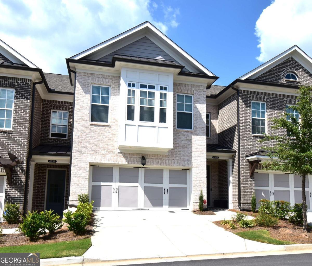 This beautiful townhome features the Ellington plan, boasting a main level entry and a driveway. Key features of this property include: a 2-car garage with additional parking in the driveway, linear fireplace, built-in wine fridge with a 155-bottle capacity, custom pantry, two custom closets, screened-in porch with sliders, shiplap entry foyer, window screens, epoxy garage floor, kitchen cabinet pullouts, built-in family room cabinets and shelving, separate tub and shower with bench in the primary suite, hardwood floors throughout, fenced-in yard, and preparation for a future elevator. The amenities package in the neighborhood is the best Peachtree Corners has to offer with 4 large green spaces, pool that backs to the river walk, pavilion that overlooks the river walk, pickleball courts, clubhouse and much more!! Walk along the river walk to the Chattahoochee! Gated community!! Here today and gone tomorrow, don't miss it!!