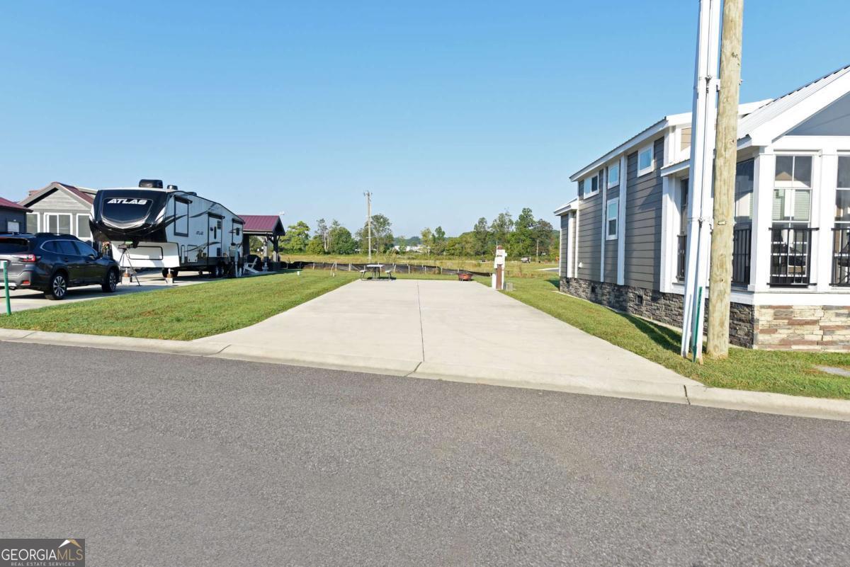 Welcome to your spacious RV lot nestled in a serene countryside setting, offering breathtaking mountain views that define the charm of North Georgia. This ultimate 5-star luxury RV park and spa is the ideal canvas for your RV or the perfect spot to create your "home away from home" tiny retreat. This backside community parcel not only provides ample space for your family, including your four-legged friends to run and play, but also features added green space for extra enjoyment. With complete hookups for water, electricity, and sewage, you can relax and immerse yourself in the beauty of the landscape while planning your tiny home build. If you're looking to share this space, our on-site management team can handle everything for you through our Short-Term Rental (STR) program even on the lot with no cabin. Experience a lifestyle filled with relaxation and recreation in our vibrant community. Enjoy sparkling pools, a fully equipped fitness center, tennis and pickleball courts, a dog park, spa, indoor sauna, and more. The quarterly fees cover yard maintenance, Wi-Fi, garbage drop-off, water services and more that make this life hassle-free. Outside the community, explore the stunning North Georgia area, from Blairsville to Blue Ridge and Hiawassee to Murphy, NC. Engage in hiking, biking, kayaking, tubing, shopping, and more. After your adventures, return home to unwind with massage chairs and a steam shower, ready to do it all over again the next day. Come where memories are made and tranquility reigns supreme!