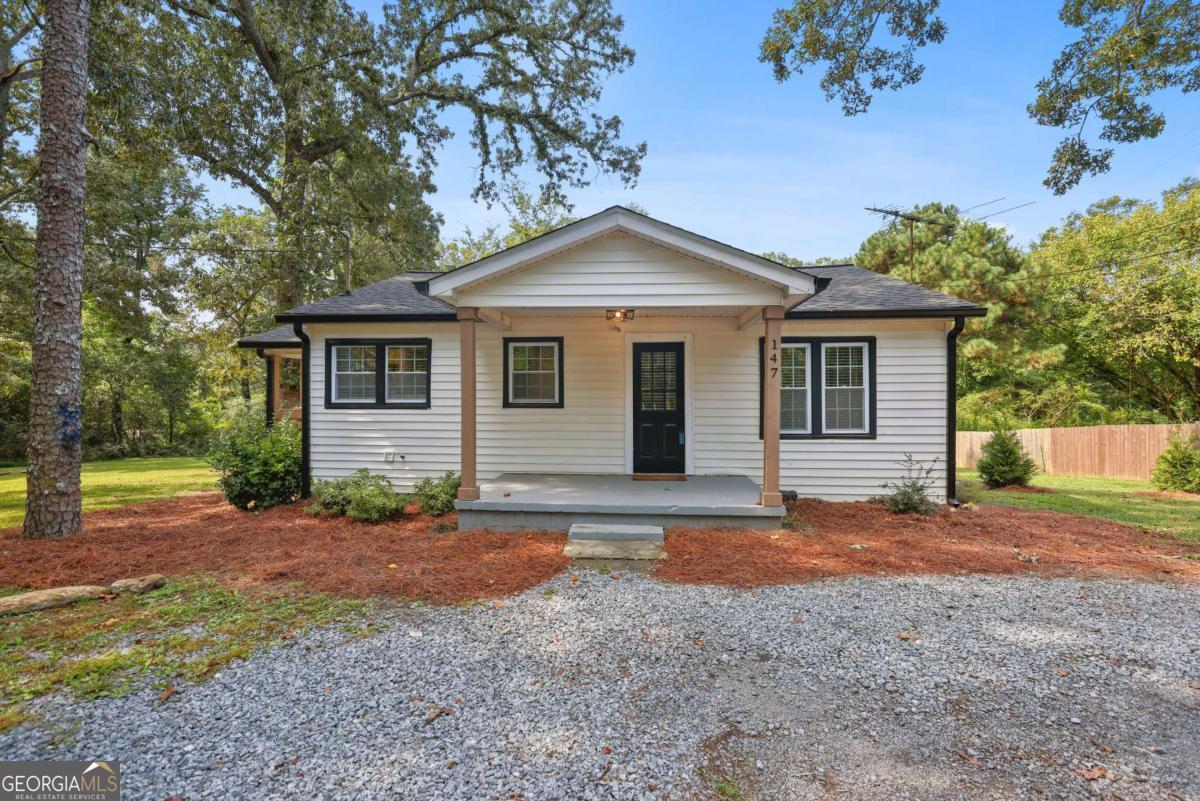 Welcome to this fully remodeled gem, thoughtfully updated (2022) with a new roof, HVAC, windows, plumbing, and more, offering peace of mind and modern comfort for years to come. Step inside to an open-concept layout that seamlessly connects the kitchen, dining, and living areas. The stylish kitchen features white shaker cabinets, quartz countertops, and stainless steel appliances, while a convenient laundry closet sits just off the kitchen for everyday ease. The updated bathroom includes a sleek modern vanity and a tub with tile surround. Throughout the home, you'll find low-maintenance LVP flooring, updated lighting, and tasteful finishes that elevate the entire space. A smart split-bedroom layout offers added privacy, ideal for roommates or guests. Outside, relax on the charming front and side porches or take advantage of the spacious, level backyard perfect for creating your dream outdoor retreat. The lot extends beyond the grassy area, providing ample space to expand if desired. Centrally located between Atlanta and popular North Georgia (approximately 40 miles to either), this home is just 1 mile from I-575 and minutes to shopping, dining, and everyday conveniences. Furnishings negotiable. Added Bonus: Take advantage of the two neighboring homes also available for sale and create the ultimate family compound!