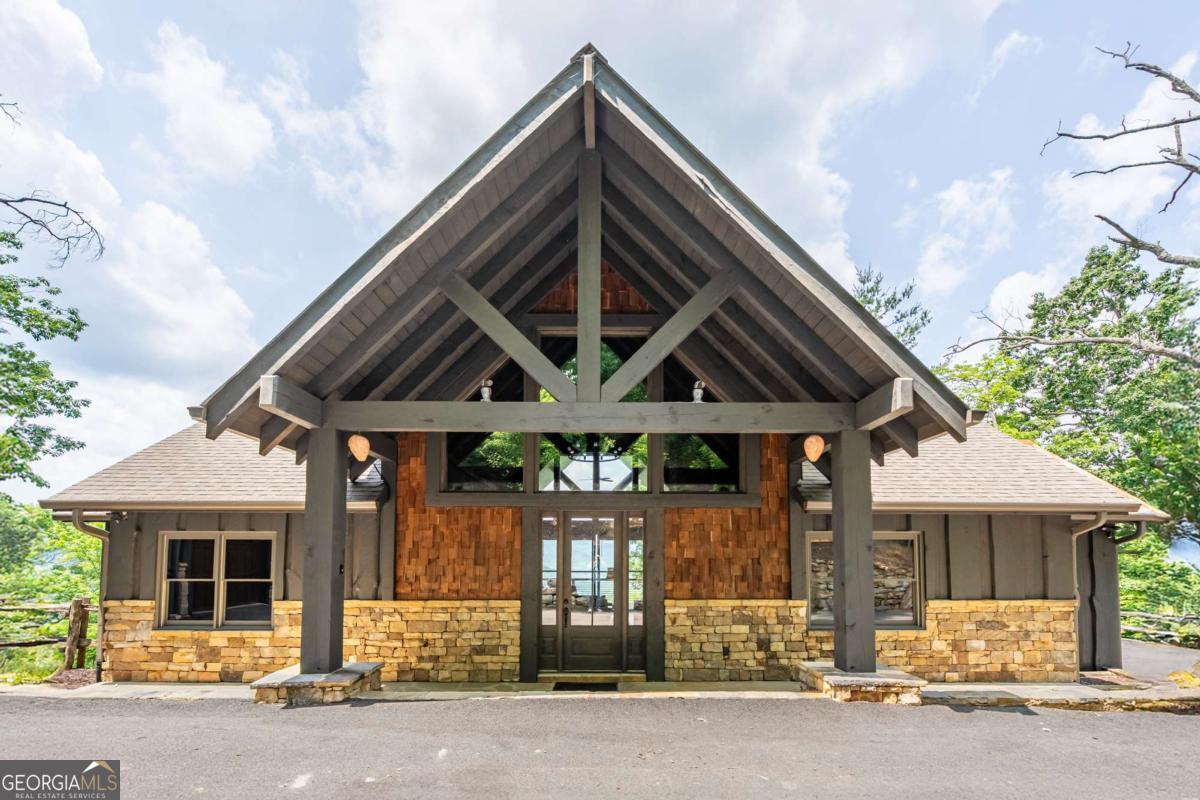 Perched at a breathtaking 2,540' elevation in the heart of North Georgia's most sought-after mountain town, this home is a masterpiece of craftsmanship and design. Built by renowned luxury builder Keith Sumner, whose homes frequently headline the Blue Ridge Parade of Homes, this estate blends bold mountain architecture with refined finishes that leave a lasting impression. From the moment you arrive, the exterior makes a statement-featuring an artful combination of stacked stone, shake siding, and live edge log trim. Inside, the home's three stunning stone fireplaces, vaulted ceilings, and scraped hardwood floors set the tone for relaxed elegance. The gourmet kitchen is equipped with Viking appliances, stone countertops, and opens into an expansive living room perfectly framed by awe-inspiring mountain views. With four spacious bedrooms, 3.5 luxury baths, and two living areas-one on each level-this home offers both privacy and functionality. Stone showers, a 45-foot wide deck on the main level, and a matching 45-foot patio below make entertaining effortless and elegant. The lower level's stone flooring adds rustic warmth while maintaining upscale appeal. The detached, heated and cooled garage includes a full bath and a spacious upstairs office that could easily function as a fifth bedroom, studio, or private guest suite. And then there's the view When people say "That's a million-dollar view!" they're talking about this house. With sweeping 180-degree long-range mountain views, every sunrise and sunset is a work of art. Whether you catch the vibrant autumn foliage, or a snow-dusted panorama in winter, you'll be left breathless by the ever-changing beauty of this mountaintop retreat. Located just minutes from downtown Blue Ridge, you'll enjoy world-class fly fishing, luxury boutiques, galleries, and an impressive culinary scene that rivals metro markets.