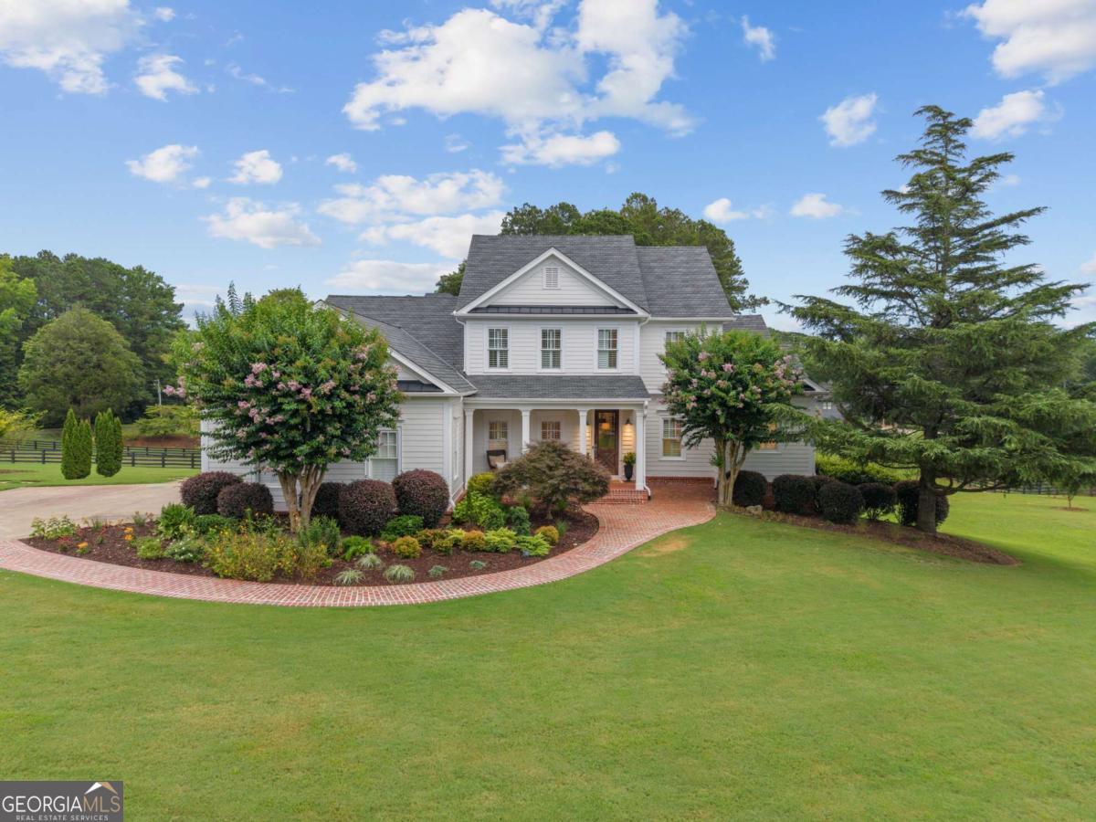 Fully renovated and move-in ready, this stunning Stephen Fuller-designed farmhouse rests on 2+/- private acres just over the Milton line in Cherokee County. Behind the gated entrance, you'll find a beautifully reimagined home blending modern luxury with classic farmhouse charm. Recent renovations include a brand-new roof, new windows, fresh exterior paint and stain, and professional landscaping. Inside, enjoy refinished hardwood floors, fresh paint, updated plumbing and electrical, new HVAC, spray foam insulation, and custom cabinetry throughout. The gourmet kitchen features refinished cabinets, marble countertops, updated appliances, a Wolf gas range with pot filler, walk-in pantry, and vaulted fireside keeping room. The adjacent fireside living room offers shiplap walls, a masonry fireplace, and double French doors opening to the expansive screened porch overlooking the private backyard. The primary suite on the main level provides a serene retreat with its own fireplace, exposed brick walls, private porch access, and a luxurious spa-like bath with Carrara marble-topped vanities, freestanding soaking tub, and oversized glass shower with body jets. Upstairs, find three spacious bedrooms with new heart pine floors and two full bathrooms. The finished terrace level is ideal for multi-generational living, with a second full kitchen, living area, bedroom, full bath, and laundry, plus direct access to the backyard. Outside, relax by the pool, dine beneath the pergola, or enjoy the professionally maintained landscaping and lush lawns. Located in the desirable Creekview High School district, this property offers convenient access to Milton, Crabapple, Alpharetta, plus just minutes to Publix, Seven Acres, and Scottsdale Farms. A rare combination of charm, privacy, and modern upgrades. This home is truly turnkey.