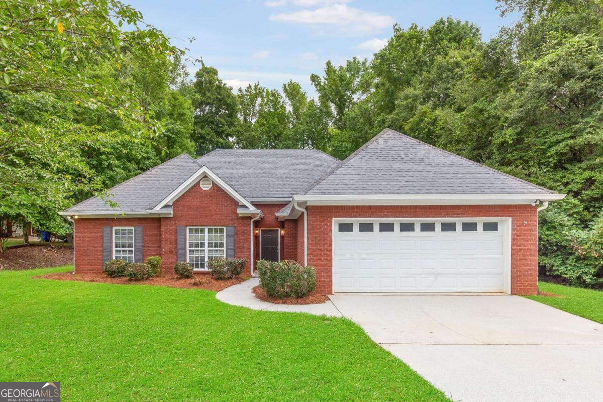Welcome to this beautifully updated, step-less four-sided brick ranch offering timeless curb appeal, modern updates, and a peaceful setting conveniently located near I-20 for an easy commute while still feeling tucked away from the hustle and bustle. With a two-car and extended parking pad you'll have ample parking for boat, RV, and more. Inside, all updates are less than two years old, including new flooring, updated appliances, fresh paint, modern lighting throughout, and more. The inviting foyer opens to a formal dining room and leads into the vaulted family room, anchored by a floor-to-ceiling ship-lap gas fireplace, a warm and welcoming focal point. The galley-style eat-in kitchen features stainless steel appliances, a subway tile backsplash, a casual dining area, and direct access to the back patio, making indoor-outdoor living a breeze. A separate laundry room with built-in storage cabinets adds to the home's functionality. The primary suite boasts double tray ceilings, a sitting room with private patio access, a jetted tub, double vanity, and generous closet space. Two additional bedrooms and a full bath complete the well-designed floor plan. Step outside to your private backyard oasis with wooded views, offering the perfect blend of nature and possibility. An extended patio and pathway create an ideal space for a fire pit, cafe lighting, for a cozy seating area, just in time for crisp fall evenings. And with no HOA, you have the freedom to design the backyard of your dreams!! Located near grocery stores, shops, dining, schools, walking trails, and recreational facilities. This home offers the best of both convenience and tranquility. A rare find so don't miss your chance to call this updated ranch your own!