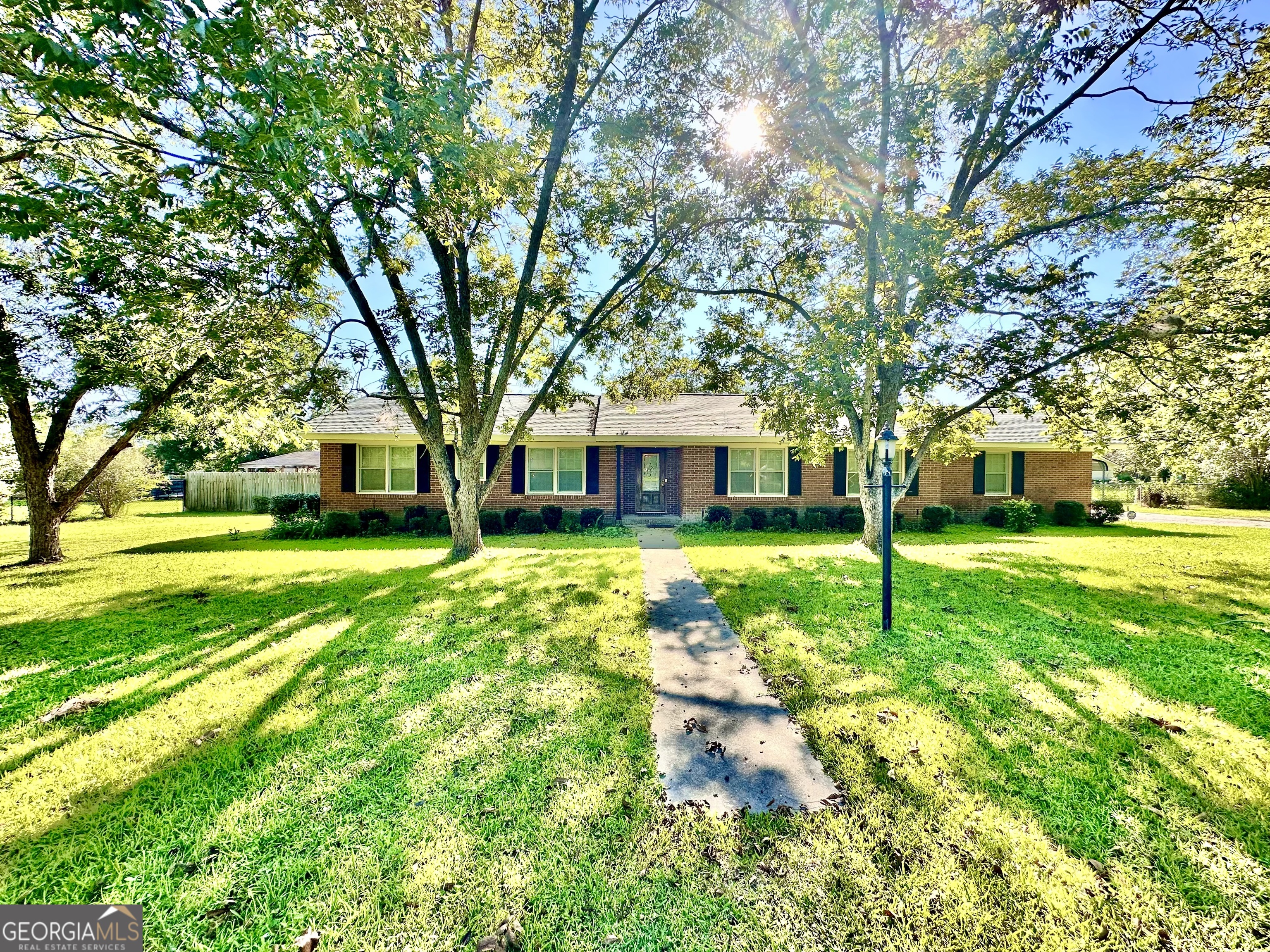 Step inside this 3-bedroom, 2-bath brick home and you'll immediately notice its welcoming charm, beginning with the entry foyer that offers a warm first impression. The front living room features a cozy fireplace framed by built-in bookshelves, creating the perfect spot to relax or showcase your favorite books and decor. Just beyond, the spacious back family room offers its own set of built-in shelves and connects to the kitchen and breakfast area, providing a comfortable flow for everyday living. The kitchen is designed for both function and connection, with plenty of cabinet space, a breakfast table area, and a laundry hook-up closet with pantry storage. It's the kind of space where you can talk with your family while making pancakes in the morning, all while keeping everything organized and within reach. Two bedrooms share a convenient Jack-and-Jill bath with a stand-up shower, while the primary bedroom connects to the hallway bath, making the layout both private and practical. From the family room, step into the bricked, screened-in back porch-a relaxing retreat that overlooks the fenced backyard and the additional storage garage building. To the side of the yard, the privacy-fenced inground pool is perfect for summer days, with both covered and open patio areas depending on whether you want shade or sun. A private changing space by the pool adds even more convenience. The attached 2-car brick carport includes a large storage area, offering plenty of room for tools, equipment, or hobbies. Blending comfort inside with outdoor living and entertainment, this home is designed for making memories in every season.