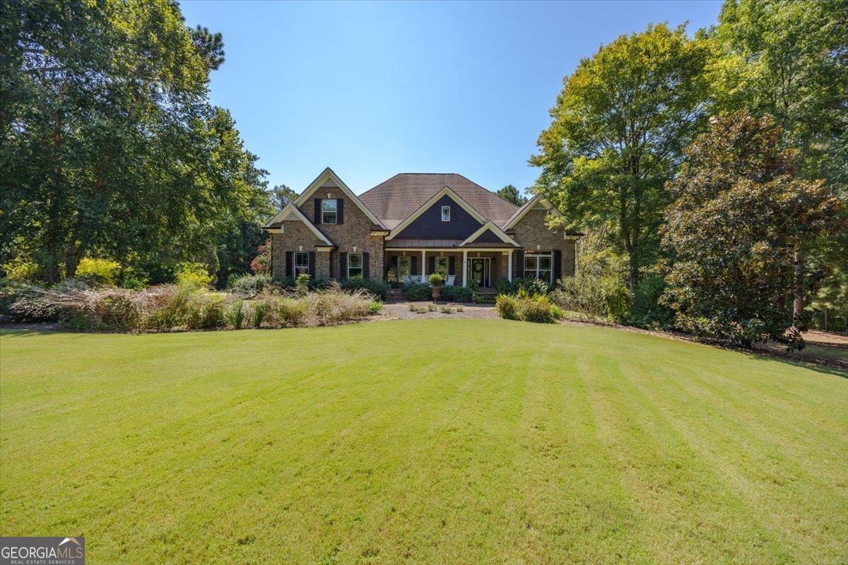 Step into elegance and comfort in this stunning home located in the gated, amenity-rich community of River Forest. Thoughtful design and timeless details set the tone throughout, with wood floors, arched doorways, and extensive trim work adding character and warmth. The main level offers both style and function, featuring a beautiful office/library with custom built-ins, a spacious dining room perfect for entertaining, and a fireside owner's suite with a luxurious feel. The breakfast room opens to a back porch overlooking the landscaped grounds-an ideal spot for morning coffee or evening relaxation. Two additional bedrooms on the main level provide comfort and convenience for family or guests. Upstairs, a versatile loft creates the perfect gathering or game room space, complemented by another bedroom, full bath, and a large bonus room with closet. The finished basement is a true extension of the home, offering a full kitchen, great room, craft room, plus two additional bedrooms and baths-perfect for multi-generational living or long-term guests. Outdoor living shines with beautifully landscaped gardens, vibrant blooms, multiple seating areas with a "secret garden" feel, a garden house with lean-to and workshop, and a firepit for cozy evenings. A three-car garage plus an additional garage with roll-up door by the basement level ensures ample storage and flexibility. With exceptional craftsmanship, abundant living space, and enchanting outdoor areas, this River Forest residence offers a lifestyle of both sophistication and relaxation.