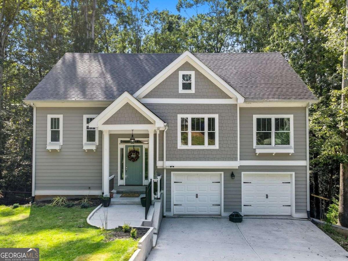 This charming split-level home is nestled in an established Lake Lanier neighborhood and offers a welcoming open floor plan with LVP flooring and a cozy wood-burning fireplace in the great room. The kitchen features white cabinetry, stainless steel appliances, and a warm, inviting atmosphere, all overlooking peaceful wooded views from the back of the home and deck. The primary suite and bath is conveniently located on the main level and includes granite countertops with dual vanities, white cabinets, a separate garden tub and shower, beautiful tile flooring, and a spacious walk-in closet. Two additional bedrooms and a full bath are also located on the main level, along with a laundry room for added convenience. The finished lower level provides two more bedrooms, one with its own private deck. This lower level space that can easily function as an office, guest room, or additional family room. A Jack-and-Jill bathroom with white cabinets and tile flooring adds both charm and practicality to this level. The home sits on a private, fenced wooded lot and is ideally located near shopping, restaurants, Simpson Park, Robinson Park, and multiple boat ramps. A large staircase in the garage leads to an unfinished basement with exterior access, perfect for storage or future expansion. With durable hardy board siding and thoughtful design throughout, this home blends comfort, functionality, and natural beauty in one exceptional package.