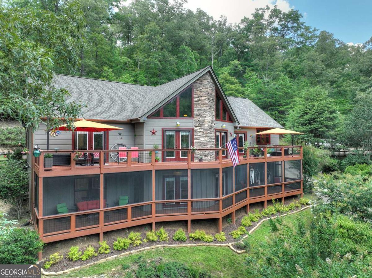 Experience unparalleled riverside living at this exquisite Prow Front home, perfectly positioned overlooking the majestic Toccoa River with large windows that flood the interior with natural light bringing the outdoors in. The Toccoa River, crown jewel of Fannin County, offers world-class trout fishing and serene canoeing right from your doorstep. This captivating home features a convenient master bedroom suite and laundry on the main level. The heart of the home is a large gourmet kitchen with stunning granite countertops. Gather around floor-to-ceiling stone fireplaces in both the main level Great Room and the expansive lower level Family Room, creating warm and inviting spaces. Parking areas include a lower level garage, an additional parking pad, and a large portico share at the front door. The exterior is clad with Hardie Board siding for low maintenance. Fiber optic internet is available! Beyond the main residence, discover an extra riverfront lot complete with a charming deck, providing an idyllic spot for relaxation by the water. This property offers the perfect blend of tranquil mountain and riverfront living, and convenient access to local amenities. Don't miss your chance to own a piece of Toccoa River paradise!