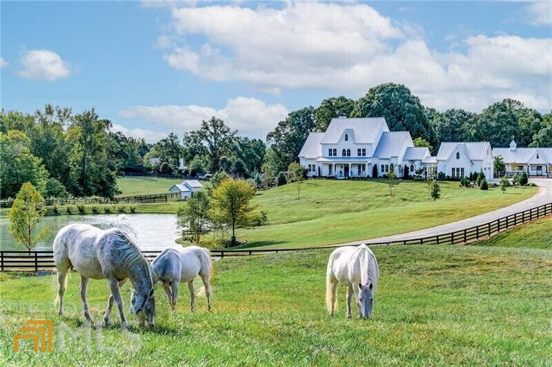 If you're searching for a once-in-a-lifetime property, look no further than Dara Hill Farm. This stunning 2019-built farmhouse estate is situated on 40 picturesque acres in highly desirable Southeast Canton. Upon entering the property, you are greeted by the beautiful equestrian landscape, rolling green pastures, and breathtaking views of the incredible 4-bedroom (plus office/5th bedroom) and 4.5-bathroom custom estate home that overlooks a tranquil stocked pond. Designed by a true equestrian, your horses and animals will be happy to call this place home in the 5-stall insulated custom barn featuring 12'x14' stalls w/ attached private runs, automatic waterers, fly spray system, and interlocking mats. The barn has a thoughtfully designed, fully fenced courtyard/barnyard w/ a climate-controlled tack room, feed room, hay room, wash stall w/ hot/cold water, and a stunning 1175 sqft Studio. There are seven fenced pastures, all w/ automatic waterers. The main house, pool, barn, and garden were all designed around a 100-year-old oak tree, which is the heart of the remarkable English-style garden. Boasting luxury finishes and impeccable attention to detail, the owners, spent two years collecting reclaimed items and antiques to build this house around. A home out of the pages of Architectural Digest, you enter through the reclaimed antique English door featuring a custom stained-glass transom. The 2-story grand foyer has balusters reclaimed from a 19th-century Philadelphia home and is decorated with an oversized Visual Comfort Movarian Star chandelier. The interior offers spacious open-concept living with beautiful rough-sawn white oak floors. The home is centered around the generously sized living and sitting room that features a fireplace w/ reclaimed mantle and beams. A continuation of the indoor living space is the rear porch which offers a beautiful, whitewashed brick fireplace w/ a gas starter, TV outlet, custom mantle, and copper lanterns. The elegant kitchen has beautiful marble counters, custom cabinetry & hardware, a 6' Lacanche range, custom white oak hood, 4' True refrigerator, Perrin and Rowe English faucet, reclaimed pocket doors from an Ohio church, and a butler's pantry w/ an additional sink and refrigerator. The main level owner's suite has Designer's Guild wallcoverings, his & her closets w/ California Closet system being installed in November, antique 19th-century French doors from Paris, antique rectangular claw foot soaking tub from Paris, vintage chandeliers, and a private screened sleeping porch w/ queen size swing bed. The main level is complete with a dining room, boot room, large laundry room w/ vintage utility sink & folding table, guest bathroom, and oversized 3-car garage. The upper level offers 3 spacious bedrooms, a large office (or possible bedroom), and 3 full bathrooms w/ designer wallcoverings, each w/ unique finishes & bathroom fixtures. Enjoy a stroll through the beautiful, irrigated gardens leading to the private pool, which includes fruit trees, shade trees, a cutting and vegetable garden, seasonal flowers, and over 300 peonies. The heated salt pool offers ample decking w/ a pergola for entertaining, Stonescape pool finish, and a raised waterfall spa. There is an original 1960s farmhouse that was fully renovated into a 1-bed and 1-bath caretaker's cottage. The property has trails throughout and on the perimeter, as well as a 1.5 Acre fenced arena/jump field. The stunning topography has lightly wooded areas, meadows, pastures, and the babbling creek that runs through the property. This is the perfect place for a daily morning walk or ride and is home to wildlife, including deer families and a stocked pond. Finally, this home is in the sought-after Creekview Highschool district. It is less than 10 minutes from 7 Acre BarnGrill, Scottsdale Farms, and Milton Publix; less than 15 minutes to Milton's Crabapple District; and just 20 minutes from downtown Alpharetta, Avalon, and GA-400.