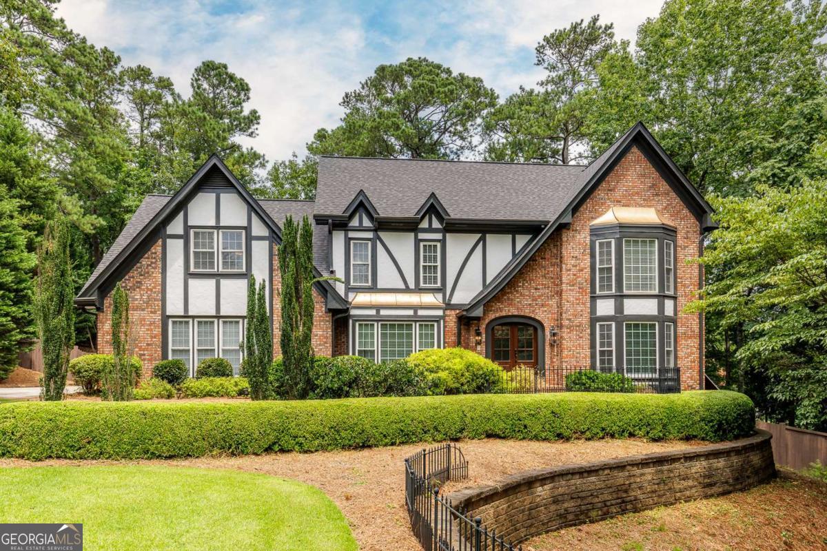 Meticulously maintained storybook Tudor nestled in a desirable cul-de-sac with a sparkling pool and numerous updates throughout. Rich hardwood floors flow through the keeping room, kitchen and dining room, while the warm and inviting family room features paneled walls, built-ins, beamed ceilings, and a wood-burning fireplace. The kitchen showcases honey-toned cabinetry, new backsplash with granite countertops, and stainless steel appliances, and opens to a spacious breakfast area and keeping room with a second brick fireplace. Recent improvements include new windows, a new roof, and updated HVAC-offering peace of mind for years to come. Upstairs, the primary suite boasts a newly renovated bath with travertine floors, granite counters, a soaking tub, separate shower, and stone wall accents. Enjoy year-round entertaining in the enclosed sunroom overlooking the pool deck with pergolas. This lovingly maintained home offers character, comfort, and convenience-and won't last long!