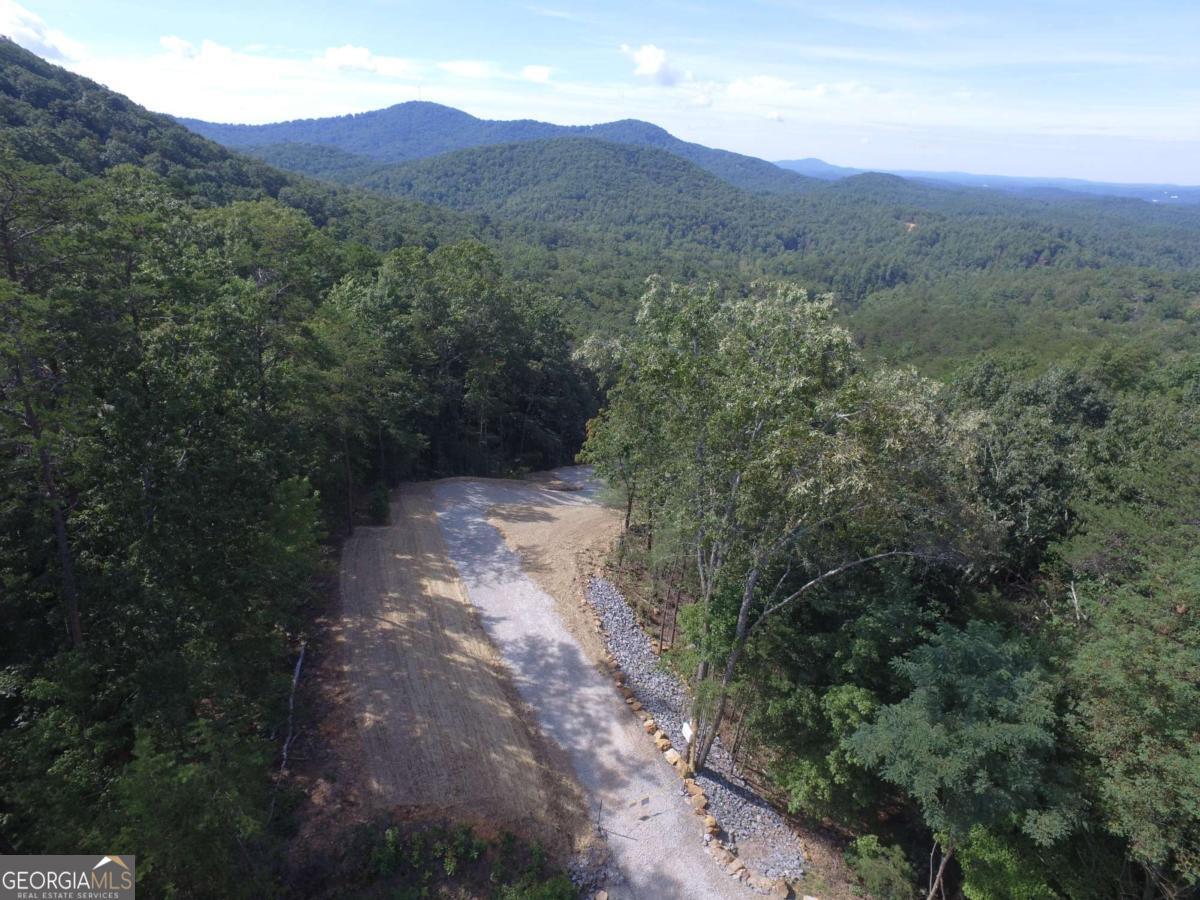 "Dream View" lot just waiting for your dream home! This gorgeous, private 6+ acre lot has been cleared to reveal the most amazing view and to make way for your mountain getaway or full-time mountain home. Get a head-start on building--the homesite is cleared and graded, the driveway is in, septic is in, erosion control completed, and grass is planted! Located in Stonecrest, surrounded by million-dollar homes, and just minutes from downtown Ellijay, you couldn't ask for a better location. This land is tucked away in a serene mountain setting but still close to all the best shopping, dining, and recreation Ellijay has to offer. Enjoy weekend brunch or a gourmet dinner just minutes from your door at the new Falls at Blue Ridge restaurant. Endless adventures await you at Carters Lake, Rich Mountain, Cohutta Wilderness, and Amicalola Falls. You're also close to what Ellijay is famous for--its apple orchards and the Ellijay Apple Festival! Blue Ridge is just a short scenic drive away as well as Blairsville and other quaint mountain towns. Stonecrest has no HOA, only minimal covenants in place to protect the integrity of the community such as maximum number of homes per acre, no mobile homes, minimum home size, etc. Short-term rentals are allowed. Power and fiber are available at the cul-de sac at the top of the driveway.