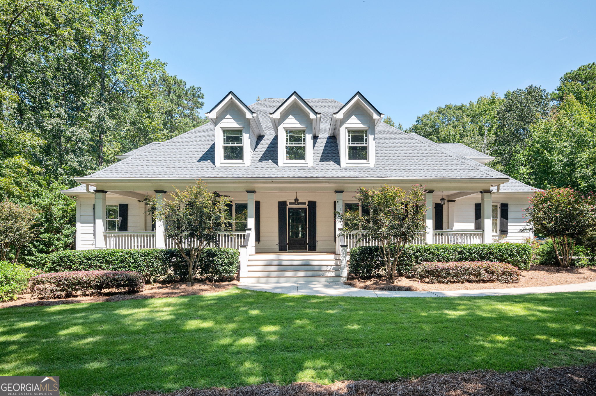 Meticulously maintained and beautifully appointed, this 5 bedroom, 4.5 bath Cape Cod is nestled on 7.91 acres in the highly sought-after Alcovy Lakes subdivision. The main level showcases gorgeous hardwood floors and a two-story fireside family room with built-in bookshelves. The granite kitchen is a chef's delight with tile backsplash, under-cabinet lighting, stainless steel appliances including double ovens, cooktop, microwave, and refrigerator, plus a breakfast room, breakfast bar, and butler's pantry. Additional spaces include a formal dining room, formal living room/office, and an oversized master suite on the main with a coffered ceiling, large walk-in closet, screened porch access, and a spa-like bath with dual granite vanity, tiled shower, and jetted tub. A spacious mudroom with built-in cabinetry and laundry sink plus a half bath complete the main level. Upstairs features a wide catwalk with hardwood flooring overlooking the family room, three generous bedrooms, two full baths and a bonus room. The finished terrace level offers incredible versatility as an entertainment space or in-law suite, complete with a family room, eat-in kitchen with stainless appliances, bedroom, tiled bath, a flex room currently used as a gym and additional unfinished storage area. The exterior is equally impressive with a full-length rocking chair front porch, side entry two-car garage, detached three-car garage, screened back porch, two decks, and a covered patio. Outdoor living shines with an 18x36 gunite pool featuring stacked stone waterfalls and an automatic cover, hot tub, firepit, and approximately 6 wooded acres providing complete privacy. Move-in ready with a newly installed architectural roof, this home is conveniently located near downtown Monroe, Athens, Social Circle, Hwy 78, and I-20.