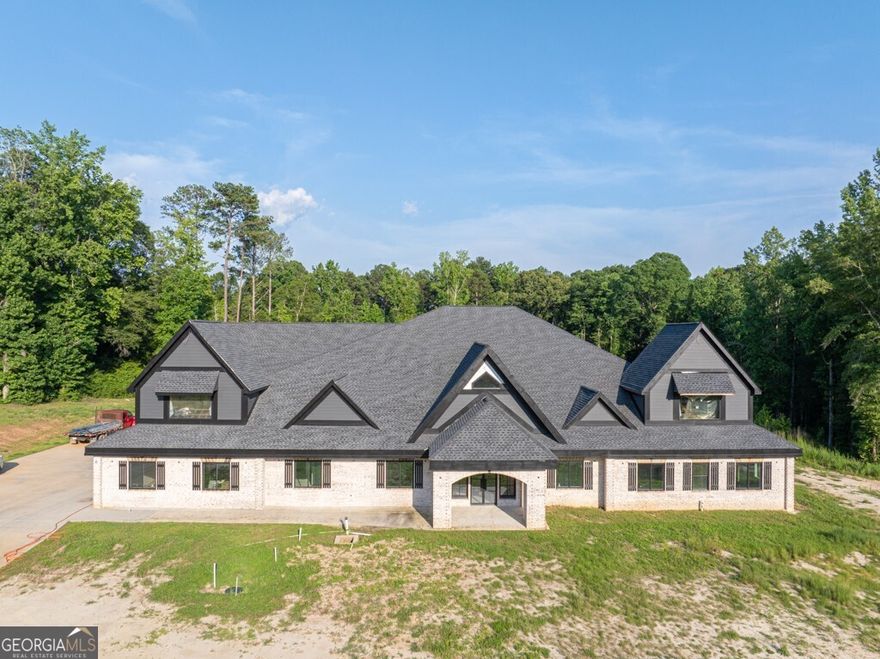 Magnificent, Amazing, Quality... These are just a few of the words used to describe this New Construction home located in Loganville, GA. Boasting 9 bedrooms, 7 full bathrooms, and 3 powder rooms. All bedrooms, including the Primary suite, are located on the main floor along with a formal living room, family room, Dining room fit for 20, Craft room, Office, Personal Gym prewired for a Sauna, Oversized laundry equipped with 3 laundry hooks-ups plus a dog-washing station. The oversized kitchen is set for a large island, two ovens, over-sized stove, 2 built-in microwaves, pre-plumbed coffee nook, space for Subzero Refrigerator. Butler's pantry leads into a truly oversized pantry wired for 2 additional freezers. My personal favorite part of the home is the Primary Suite. Floor-to-ceiling fireplace, Walk-in shower for 2 (really could fit way more!) Overhead Rain waterfall with two shower hooks ups, Step-up Jacuzzi tub with waterfall accent wall, 3 vanities, and a TWO-STORY Closet!!! Space GALORE! There are truly far too many details to list, but this home is well thought out and is a must-see. The Seller has dedicated one room as headquarters to go and adjust all the functionality of the home. Also, there is another room dedicated to all the drawings/ engineering of the home so if there is ever a malfunction, it can easily be located. There is another room which is also a favorite of mine, and that is the Decorations room!! You can easily move all of your holiday decor to one room, shut the door, and be ready for the next season. The house has been fitted for 5 HVAC units, 2 Water heaters, and has 2 septic systems installed. Seller Upstairs is truly an entertainer's dream equipped with a room for Video Gaming, A full game room space, A cathedral-style theater, and a full Kitchenette. Also upstairs is another flex room or could be a 10th bedroom, full bath, and powder room. Are you a Car Enthusiast? Great because we have you covered with an 8-car garage prewired with an electric charging station for your car and your motorcycles! Outside of the home as you wander almost 11 acres you will find a 3200-square-foot shop fully run with power, water, and a powder room. No need to wait for Summer to swim when you can enjoy the heated in-ground 18x40 swimming pool and Jacuzzi. Several fenced-in areas to home all your furry friends! Pastures, chicken coops, and pig pens on site! And we can't forget about the custom-built dog palace alongside the fenced-in pasture! Please check out the Virtual Tour attached to get a better idea of truly how amazing this home and property are! Seller had exterior color changed from red to Tricorn black. It looks amazing!