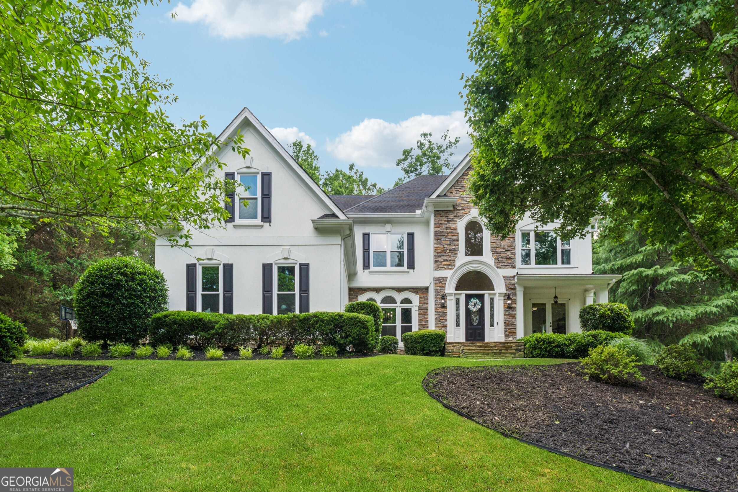 Welcome to 712 Brookshade Parkway where a top-to-bottom renovation meets one of Milton's most sought-after communities, just minutes from the heart of downtown Alpharetta. This stunning 6-bedroom, 5-bathroom home is filled with custom upgrades and thoughtful details throughout. Perched atop a hill with an oak tree-lined driveway and flat backyard, this hardcoat stucco home offers the perfect combination of luxury and privacy. Enjoy a fully renovated chef's kitchen with quartz countertops, a custom vent hood, open shelving, and a spacious scullery with wine fridge. A large window-filled family room and breakfast area overlooks your level, walkout backyard. Outside, the brand new custom outdoor kitchen, stone patio, and fire pit create the perfect space for entertaining. On the main level, you'll also find a guest suite with a fully updated bathroom featuring a walk-in shower and custom vanity, an office space, and large dining room. Upstairs, the expansive primary suite includes a fireplace, sitting room, and a spa-like bathroom with a freestanding tub, oversized shower, and custom white oak double vanity. Plus, the walk-in closet is truly a room of its own. Three secondary bedrooms, one with an ensuite and the others sharing an updated jack-and-jill bath, complete the second level. Don't forget to check out the fully finished terrace level complete with hardwood floors, a custom wet bar, home gym with rubber flooring, and media room. There's even room for further expansion with two unfinished spaces, currently utilized as a workshop and storage with custom built wooden shelving. New windows installed in October 2024 and a brand-new roof to be installed next week are just the cherry on top. Live just minutes from top schools, parks, and the dining, shopping, and charm of downtown Alpharetta with the quiet and privacy characteristic of Milton.