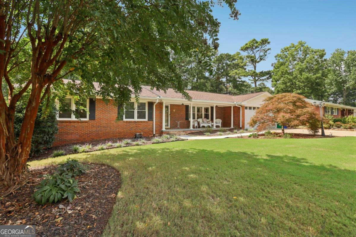 Come discover this lovingly maintained brick ranch, where timeless charm meets modern updates and abundant living space. A wide, welcoming front porch sets the stage for relaxed evenings in a rocking chair, enjoying the quiet comfort of Georgia living. Inside, beautiful hardwood floors stretch across the main level and a designer remodeled gourmet kitchen with granite counters, double ovens, tile backsplash, and pull-out cabinetry will inspire and delight your inner chef! The cozy family room, anchored by a brick fireplace and custom built-ins, seamlessly opens into a stunning 21' x 14' sunroom. Designed with skylights and expansive windows, this light-filled retreat frames beautiful backyard, wildlife, and wooded views, offering a space to truly savor-delight in hummingbirds visiting the perennial hibiscus, squirrels playfully navigating the trees, and the ever-changing palette of blooms that transform the landscape from the vibrant colors of spring to the serene stillness of winter, with each season offering its own unique beauty. Complete with a convenient utility sink, it's the perfect spot to enjoy morning coffee, unwind with evening wine, or host gatherings year-round. Three bedrooms and two full baths, including a serene primary suite, complete the main level. The fully finished basement is a true extension of the home, designed for recreation and versatility. A spacious entertainment room with a wet bar offers plenty of room for games, media, or gatherings, while two additional rooms can easily serve as bedrooms, offices, or hobby spaces. A full bath and dedicated laundry room complete the lower level. With its own private outdoor access, this area offers excellent potential as a rental suite or an ideal setup for comfortable multigenerational living. Outside, the backyard is your own private oasis! Enjoy a private fenced yard with lush landscaping, charming arbors and a dedicated workshop. Whether entertaining friends, gardening or simply relaxing to the sights and sounds of nature, this peaceful retreat is designed for year-round enjoyment. Recent upgrades include new roof (2023), HVAC (2021), waterproofing (2025), and double-pane windows. All appliances remain. Fantastic location just minutes to downtown Tucker, Stone Mountain Park, Northlake Mall, Decatur, I-285, I-85, and Hwy 78. Don't miss this exceptional home-schedule your private showing today!