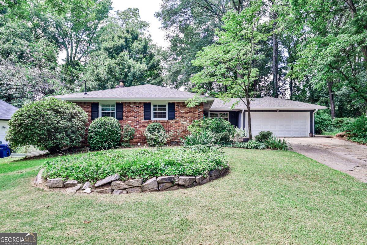 Amazingly peaceful home within walking distance of downtown Clarkston. As you enter the front door you feel right at home. The open living room plan with brick fireplace welcomes you. The living and dining rooms glow with light from the central skylight. To the left of the entry off the dining room is the large kitchen leading to the mudroom, laundry and entry to the two car garage. The bedrooms and central bath are accessed on the hall off the living room with the master bedroom and bath at the end of the hall on the left. Two additional bedrooms are on the right side of the hall. Exiting to the rear of the house from the living/dining rooms you will find the peaceful screen porch where you can sit and look out on the parklike back yard. Shaded by trees with grassed sitting areas you can feel any stress melt away. A separate garden area on the left side of the house is perfect for your vegetable or cut flower garden. This house has been lovingly maintained and is ready for you to move right in.