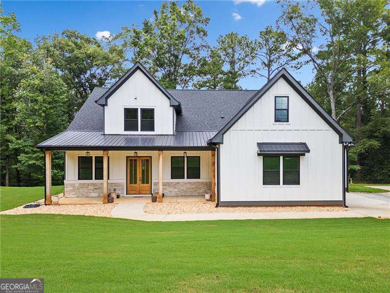Welcome to this exceptional 4 bedroom, 4 bathroom modern farmhouse nestled on a beautiful wooded 1.36 acre lot with NO HOA. Designed with both elegance and comfort, this home boasts soaring 10-foot ceilings on the main and breathtaking two-story windows that flood the space with natural light. Step inside the double front door to find LVP flooring, a dramatic floor-to-ceiling stone fireplace in the living room and a chef's dream kitchen! The kitchen features inset soft-close cabinetry, quartz countertops, a black granite island with an apron-front farmhouse sink, double ovens, a pot filler and stainless steel appliances. Just off the kitchen is a fabulous and spacious butler's pantry with space for a wine-fridge. A charming breakfast area overlooks the covered patio, perfect for enjoying morning coffee or hosting guests. You'll also find a separate formal dining room and a convenient butler's pantry for easy entertaining. The main-level primary suite is a true retreat with a spa-like bathroom offering a marble double vanity, a luxurious soaking tub, and a separate tiled shower. An additional bedroom on the main level makes an ideal office or flexible guest space. Upstairs, a beautiful staircase leads to a versatile large, open loft area, along with two generously sized bedrooms and 2 full bathrooms - one bedroom has an en-suite bath. This energy-efficient home is equipped with spray foam insulation, a tankless water heater and a spacious 3-car garage. With timeless charm and modern features, this home has everything you could ask for.