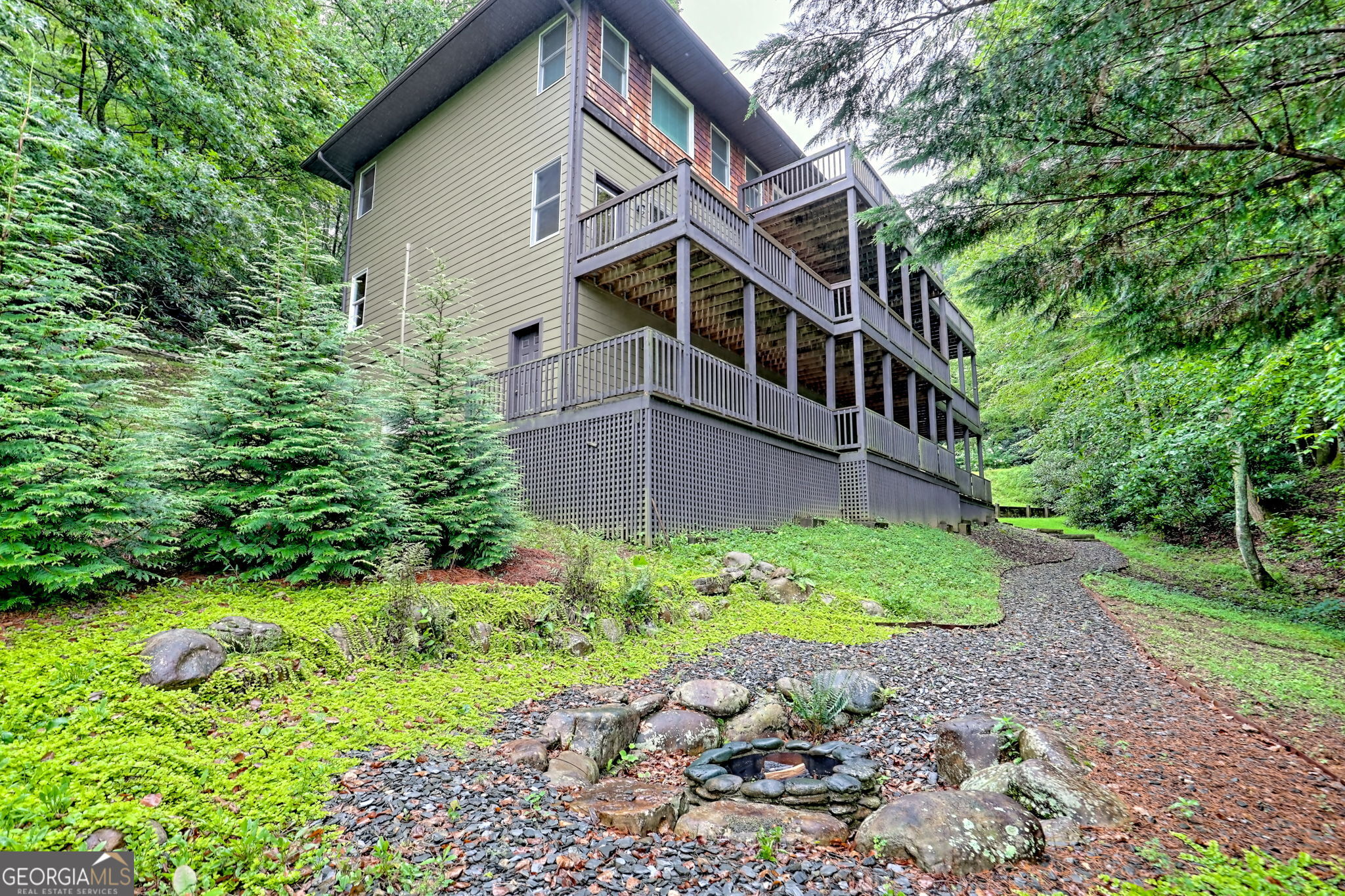 Stunning, Sky Valley Golf Course Home featuring 4 large bedrooms, 4 full bathrooms, 2 half baths, 3 floors, 3 fireplaces, several decks, a lovely flowing creek with a landscaped sitting area and a firepit. Each bedroom has a private full bathroom, large closets, and a beautiful view. The Great Room has a hand-chiseled rock fireplace, and wide planked hardwood floors throughout the Main Level. The Kitchen features Stainless Steel Appliances, Gas Range, beautiful granite countertops, a Farmhouse Sink, Large Pantry and Laundry Room. Main Bedroom has a private entrance to the Back Deck, his & her Custom Closet System and tiled bath with full steam shower. The Upper Floor has 2 Large Bedrooms, a Vaulted Living Room with Built-In Office, another pantry with Washer & Dryer Hookups, half bath, private front balcony, and entrance to the back decks. The Lower Level has a large room and Unvented Gas Fireplace, designated Sitting Area, Game Room area, Office area, a large Storage closet, and a 21x28ft Workshop. Direct walk out to the landscaped yard overlooking the 10th Fairway of the Golf Course. Convenient, walking distance to all the amenities of Sky Valley Golf Club from the yard, yet private, being nestled behind trees and Mountain Laurels. Fully Paved with easy access and plenty of parking for guests. Covered front porch with landscaped yard, including a dry creek bed. With your paid membership to the Sky Valley Golf Club, you can enjoy golf, pickleball, croquet, pool, weight room, and fine dining, but Club Membership is not required to enjoy the views, walking trails, and park areas. Only 20 minutes to fine dining and shopping in Highlands, NC, and Clayton, GA.