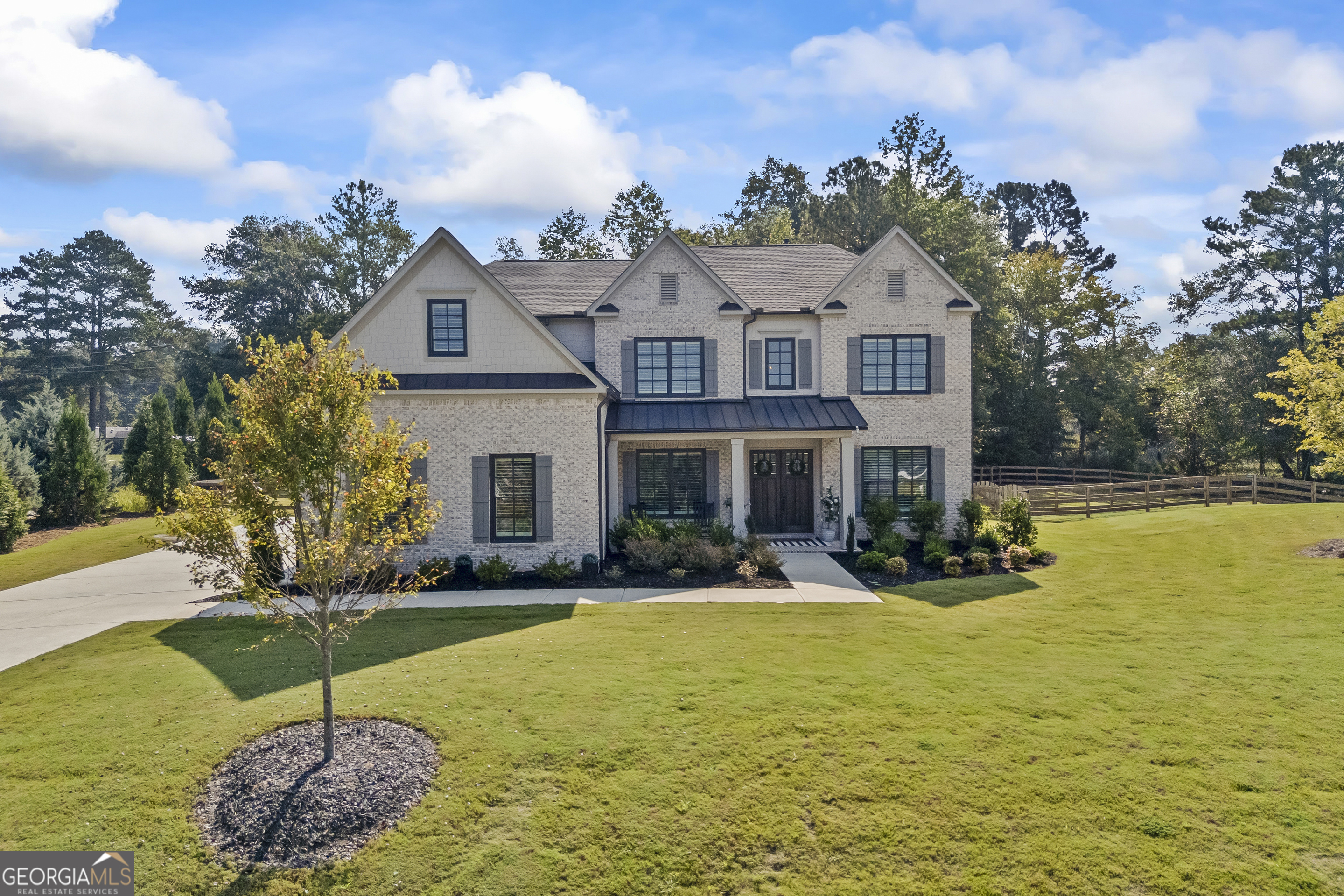 Nestled on a serene cul-de-sac lot within the exclusive Grand Reserve community, this striking Toll Brothers Payton model with a 3-car garage built in 2023 delivers refined comfort on a generous 1.05-acre setting. Step inside this nearly 4,500 sq ft home of meticulously designed living space, featuring a wide-open floor plan ideal for modern lifestyles. The gourmet kitchen stands as the heart of the home, equipped with Wolf appliances-including a 6-burner gas range and double ovens-an expansive walk-in pantry, and a smartly located mudroom for seamless daily routines. Adjoining the kitchen is an expansive, sun-lit family room, anchored by a grand fireplace flanked with built-ins and a dramatic stacking glass door system that invites effortless indoor-outdoor living and overlooks a private fenced backyard perfect for al fresco gatherings or a future pool. The main level also includes a versatile bedroom with ensuite bath, a dedicated home office, half bath and a formal dining room-ideal for entertaining or hosting family gatherings. Upstairs, a luxurious primary suite awaits with a spa-like bath and ample custom-designed closet space. Three additional well-appointed ensuite secondary bedrooms offer comfort and privacy. Community amenities enhance everyday living-enjoy access to a community clubhouse, swimming pool, tennis courts, and beautifully maintained sidewalks and street lighting. Located just minutes from downtown Roswell, Alpharetta, and Milton, this home delivers not only luxury but also lifestyle convenience, with easy access to premier dining, shopping, and entertainment options. Top-rated schools include Crabapple Crossing Elementary, Northwestern Middle, and Milton High School.