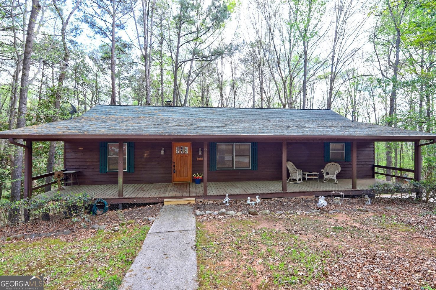 Tucked away on a serene, wooded lot, this move-in-ready, charming home welcomes you with a full-length covered front porch, perfect for relaxing. Inside, the spacious great room boasts a beamed ceiling, a floor-to-ceiling stone fireplace, and a high-efficiency pellet stove, perfect for cozy winters. The driveway leads you through the trees of this 3.5+ acre lot to the home. It's perfect for your morning coffee or sitting in your rocking chair on a rainy day. The fireplace features a pellet stove, capable of heating the entire house and reducing your electric bill in the winter. There is also a furnace if you prefer, and the fireplace can be converted back to a wood-burning fireplace. Walk out onto the spacious back deck from the great room, and you are surrounded by nature. The kitchen offers ample cabinetry, counter space, and a breakfast bar. The owner's suite boasts a walk-in closet, en-suite bath, and French doors to the back deck, two additional bedrooms, and a full bath complete the main level. A large unfinished basement room offers endless possibilities. The oversized garage accommodates three large vehicles, and a covered carport can accommodate an RV or boat. The house is connected to public water, but there is also a well that is convenient for washing vehicles, or for irrigation, pressure washing, etc. There are spigots for accessing that water on the well house and by the turnout in the driveway. Enjoy privacy, space, and nature. Schedule your showing today!